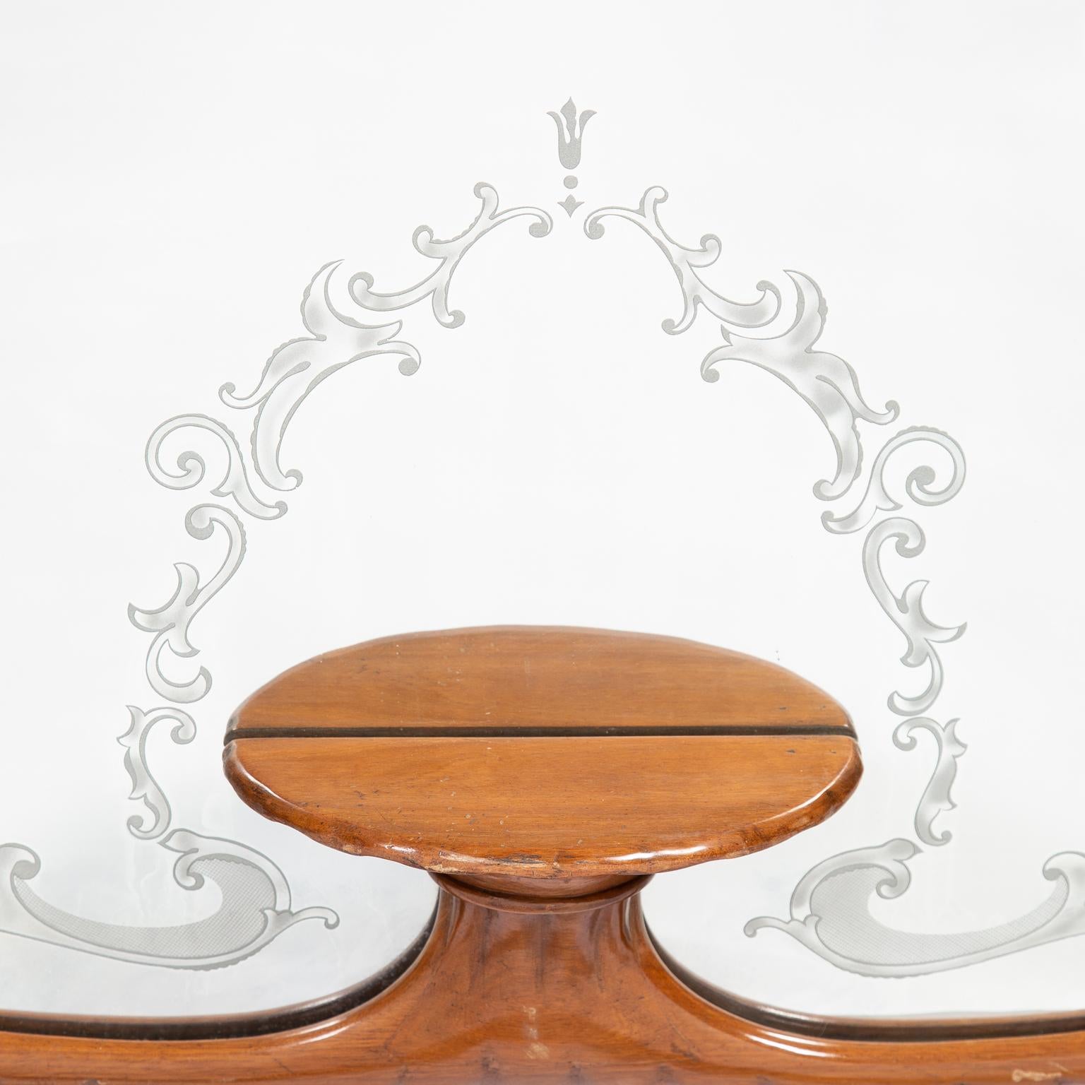 Mahogany frame mirror with scallop shaping incorporating a small lower centre shelf. The mirror glass features a border with an etched scrollwork design.