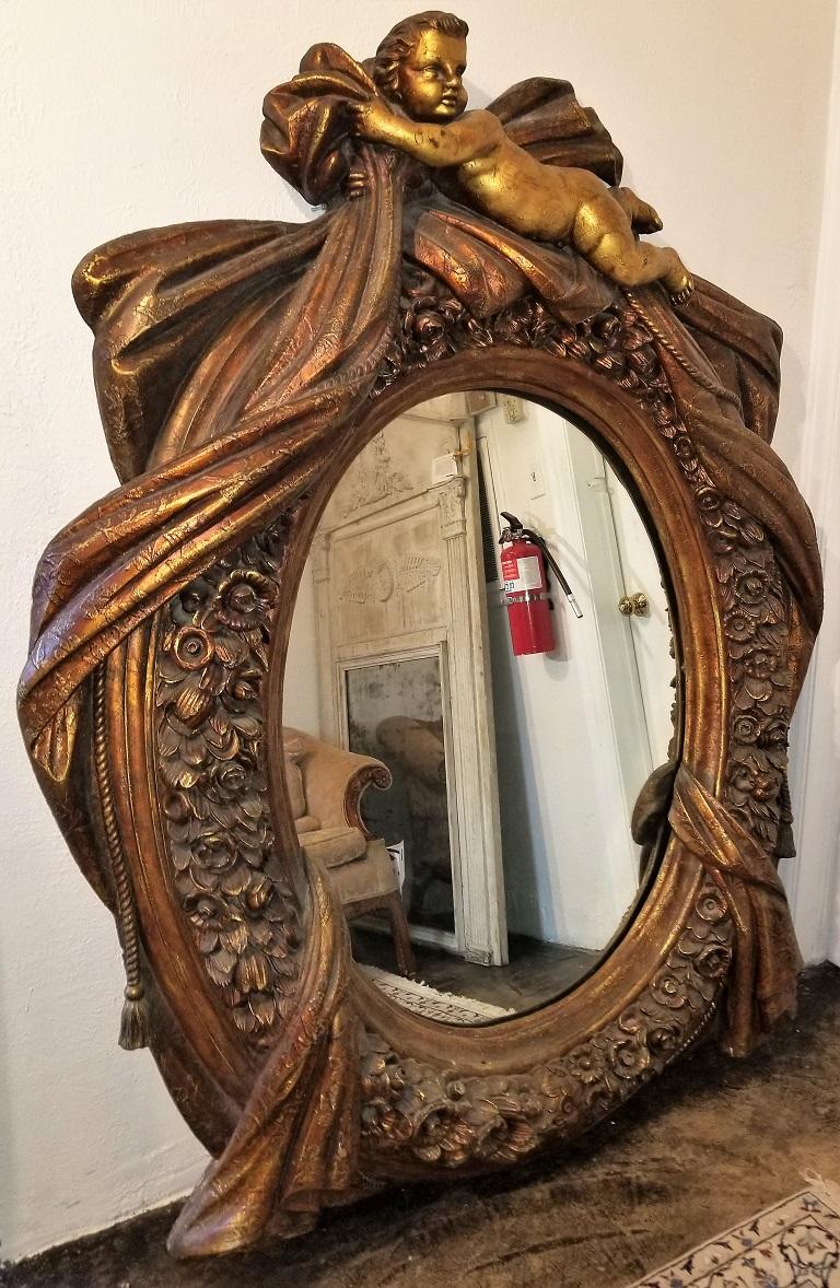 Presenting a large Italian gilt Cherub or Putti mirror frame.

Classically Italian in style with Putti or Cherub draped across the top, with swags and flowing robes on either side. The mid-section has floral bouquets.

Heavy piece intended for wall