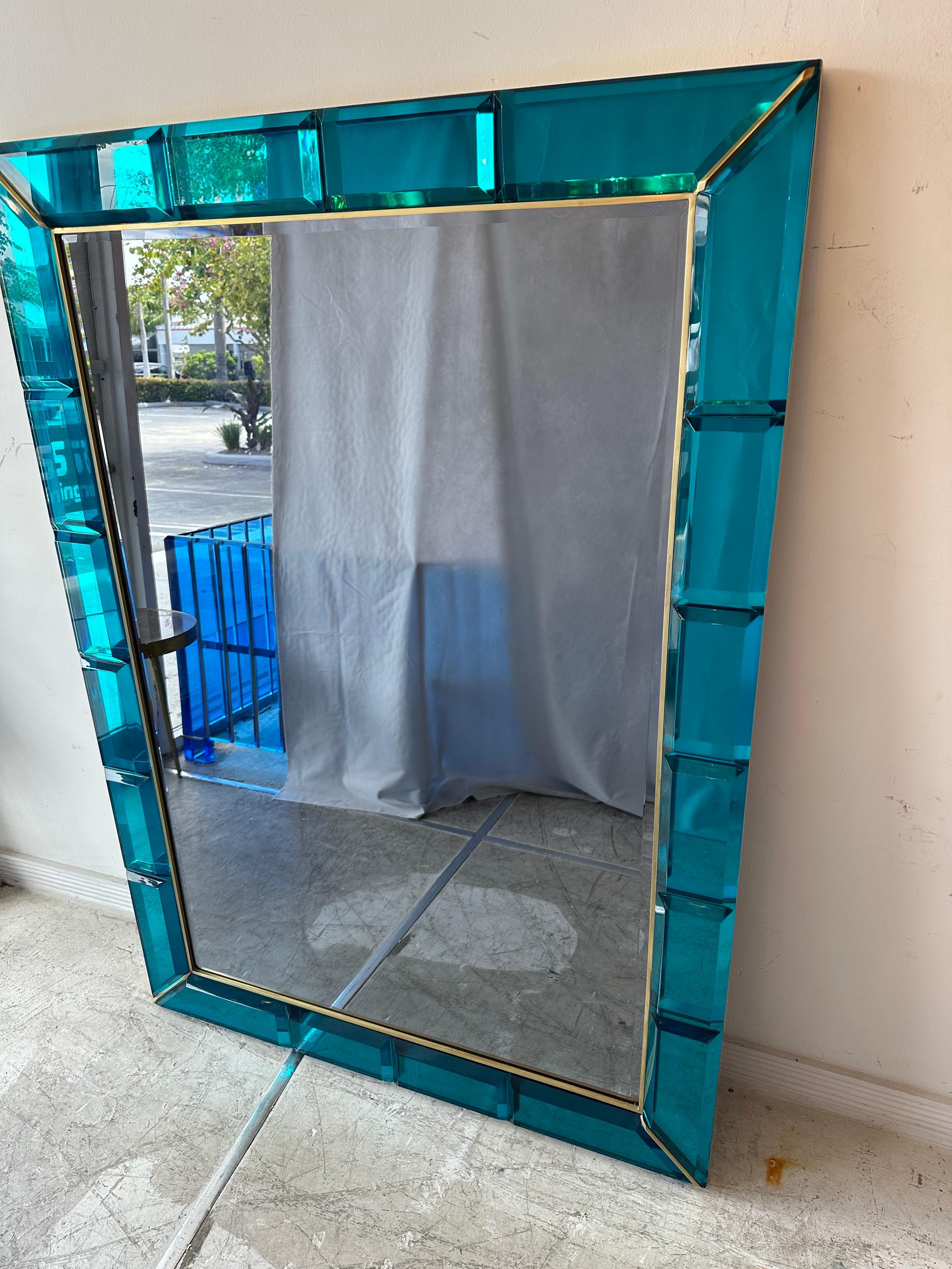 A large and very stunning Italian mirror, hand crafted of gem cut thick aqua blue lucite with polished brass trim, circa 1970s-1980s. The mirror is in wonderful condition.