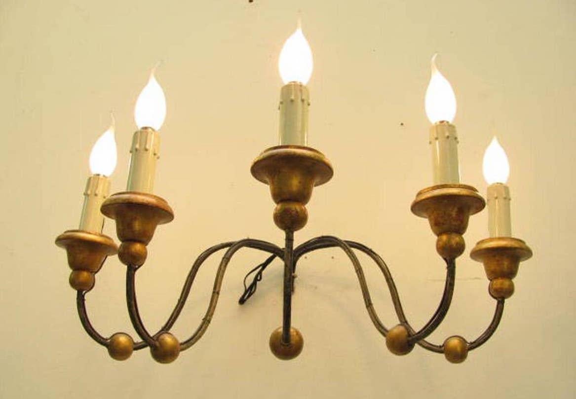 A large five-arm Italian sconce, five curved iron curved arms decorated with gilded walnut elements, ending with turned gilded walnut bobeches and candles arranged for Edison 14 bulbs. 

Working wiring for European standards, it comes from a private