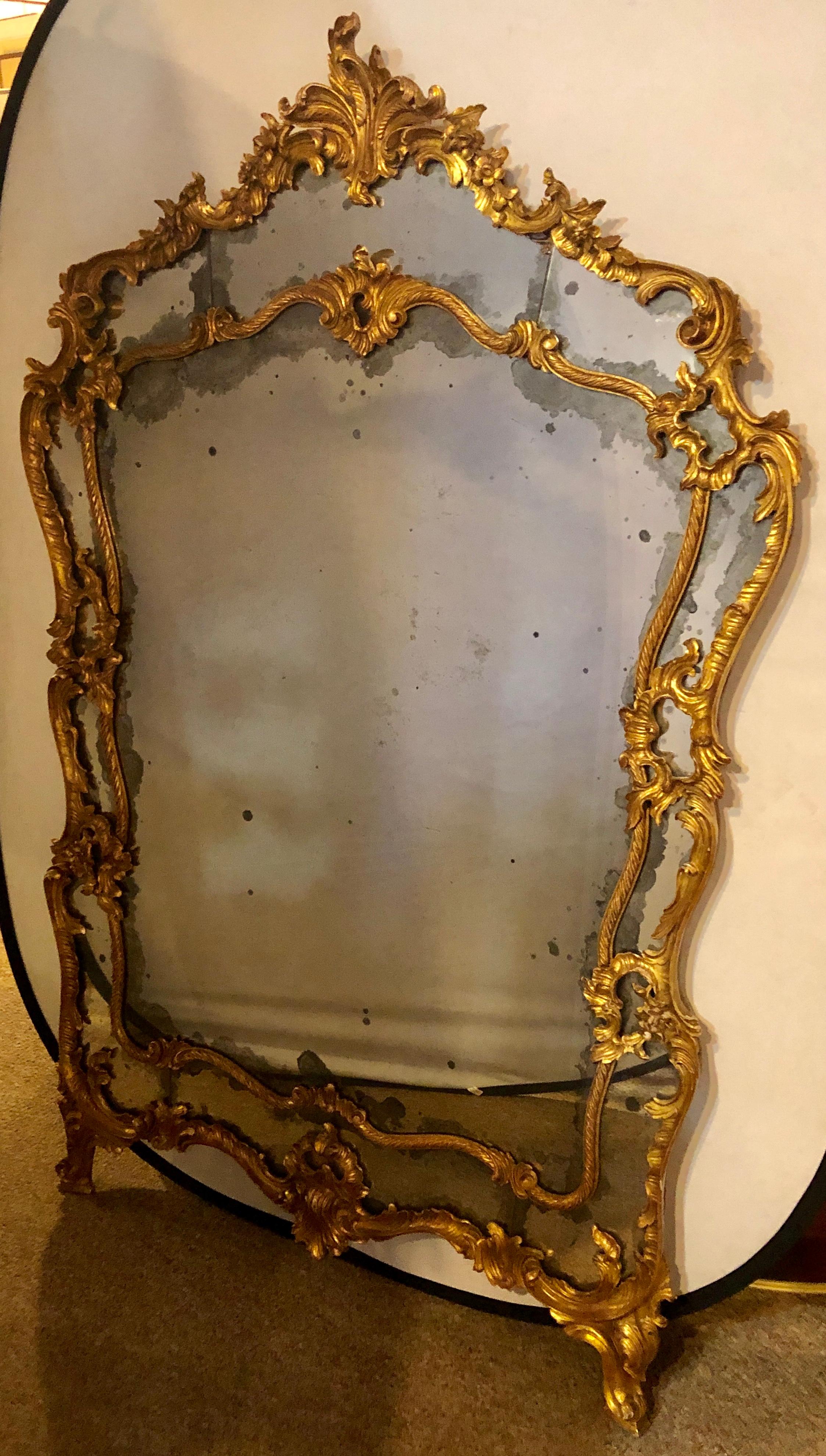 Late 19th century large Italian Louis XV style giltwood wall console or floor mirror. This palatial finely carved mirror stands a whopping near six feet tall. The scroll and floral carved frame is nothing short of spectacular. This large and