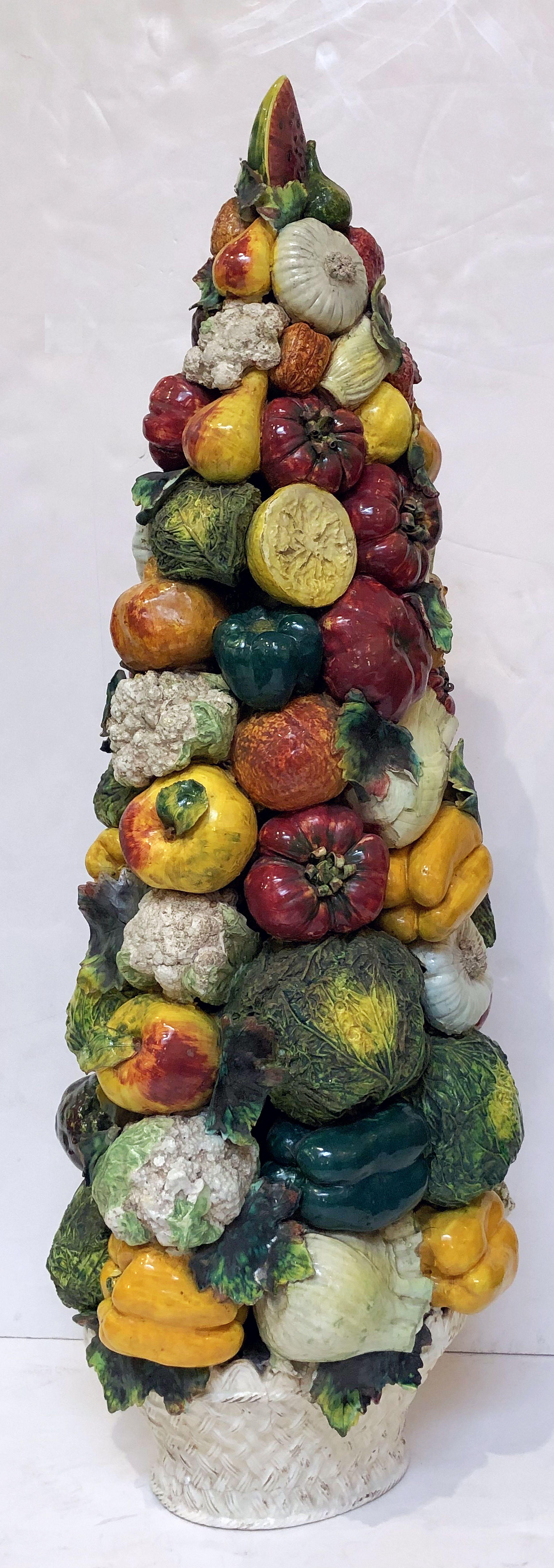 A fine Majolica vegetable tower or topiary, attributable to the ceramic artisans of Este, Italy, featuring a naturalistic relief of vegetables upon a woven basket base.

Measurements: H 37 3/4 inches x W 14 1/2 inches x D 11 inches.