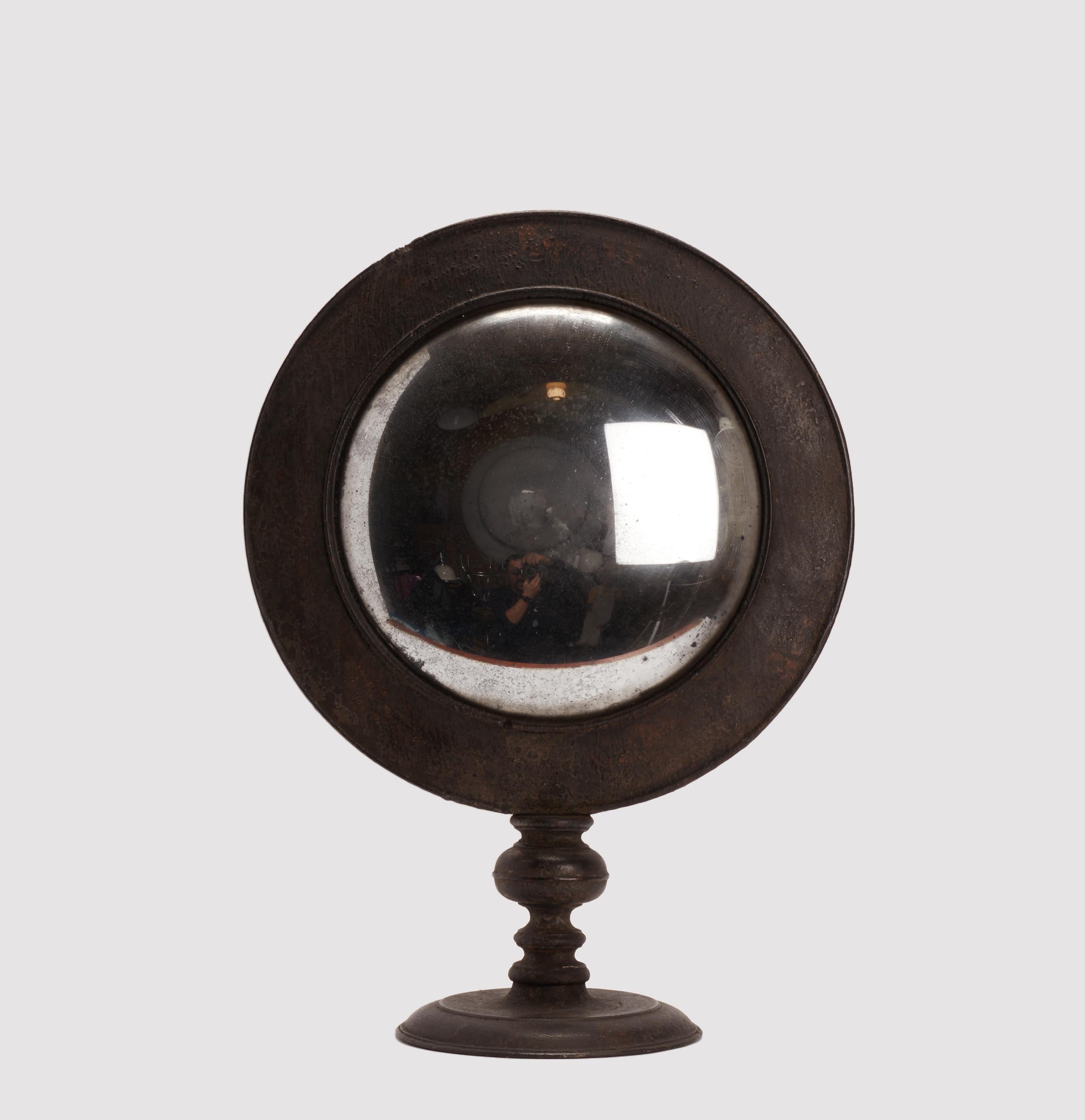 A large Wunderkammer convex round table mirror with black wooden frame mounted over a black round wooden base.