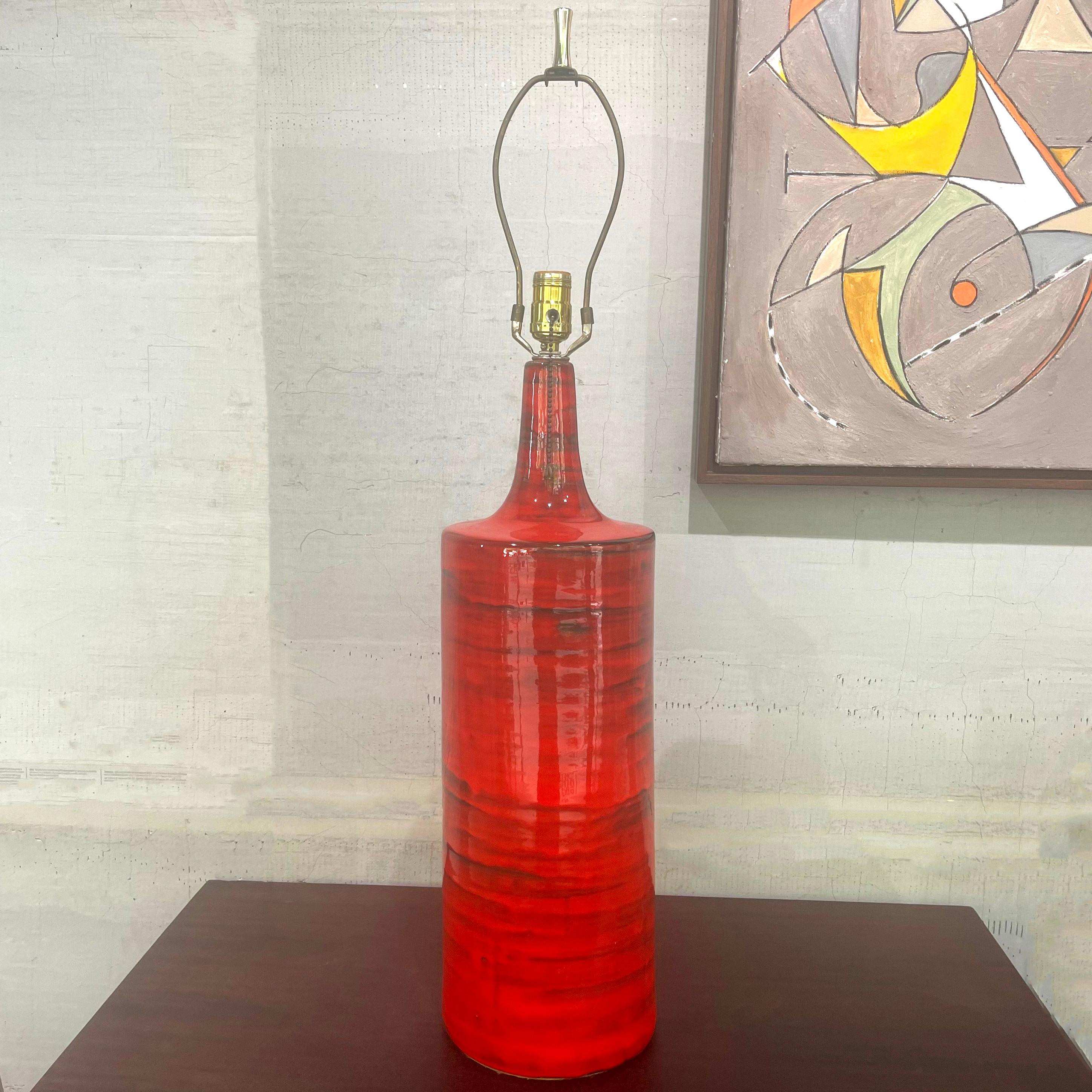 This striking modernist, Italian mid-century art pottery table lamp features a 10 inch diameter cylindrical base fired in a bold orange glaze with brown/black striations throughout giving the lamp a textured feel. The height from the base to the