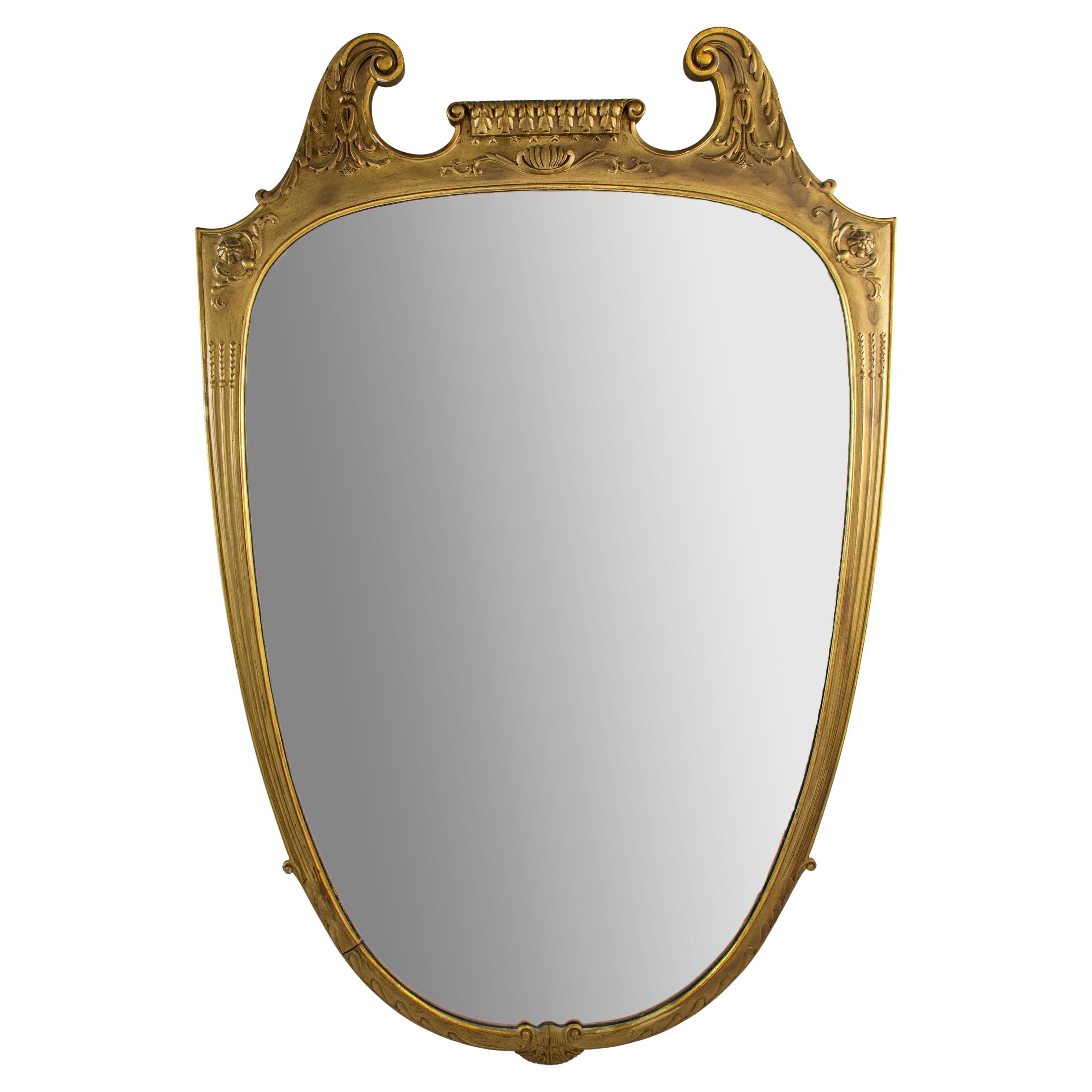 Grande specchio a forma di scudo finemente intagliato in legno dorato. Condizioni vintage molto buone.
Nello stile di Paolo Buffa, il famoso designer italiano degli anni 50'.
Altezza cm 145 
