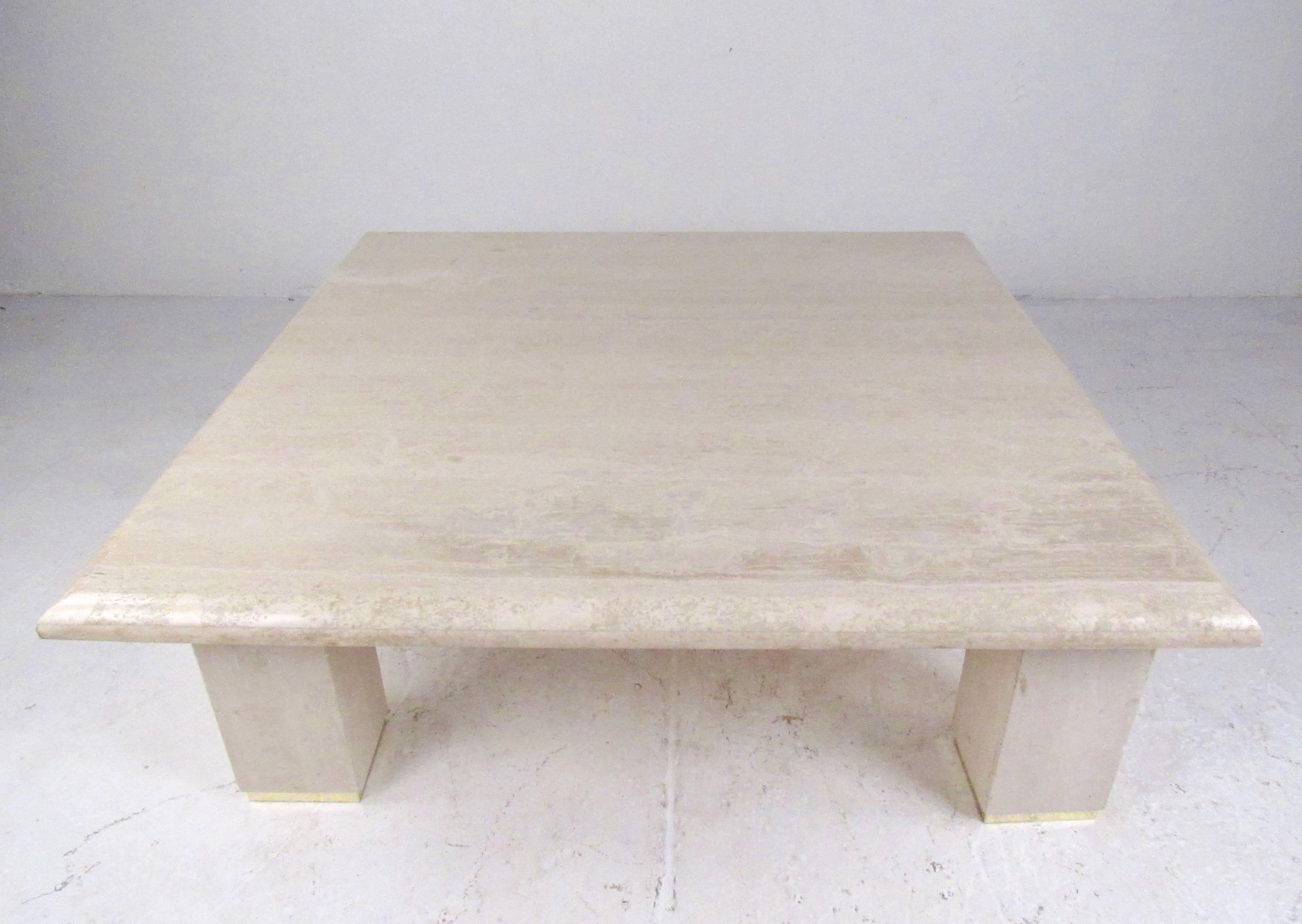 This stylish Italian Modern coffee table features a large travertine top with four pillar style travertine legs. Brass trim around the feet of the legs adds to the Mid-Century Modern appeal of the piece. Substantial size is perfect for large home or