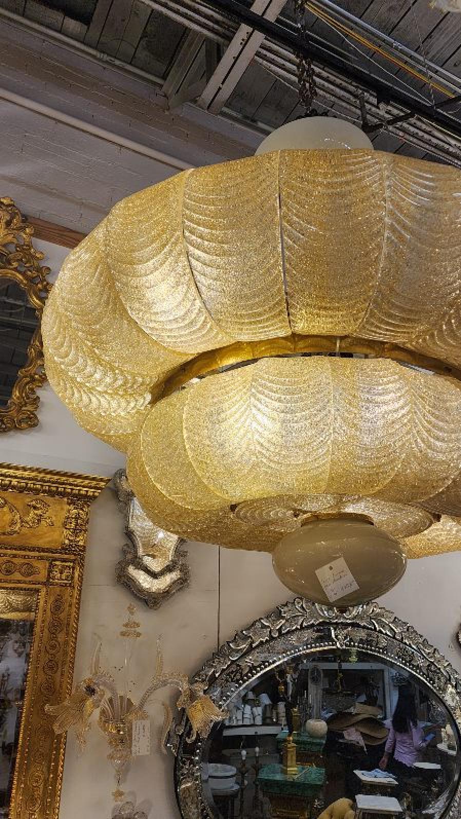 This listing features a beautiful large Murano Glass Chandelier, with cascading feather-like yellow tinted glass ornaments, and lights behind that leaves a gorgeous glow that would add personality to any living space.  

Murano glass dates back to