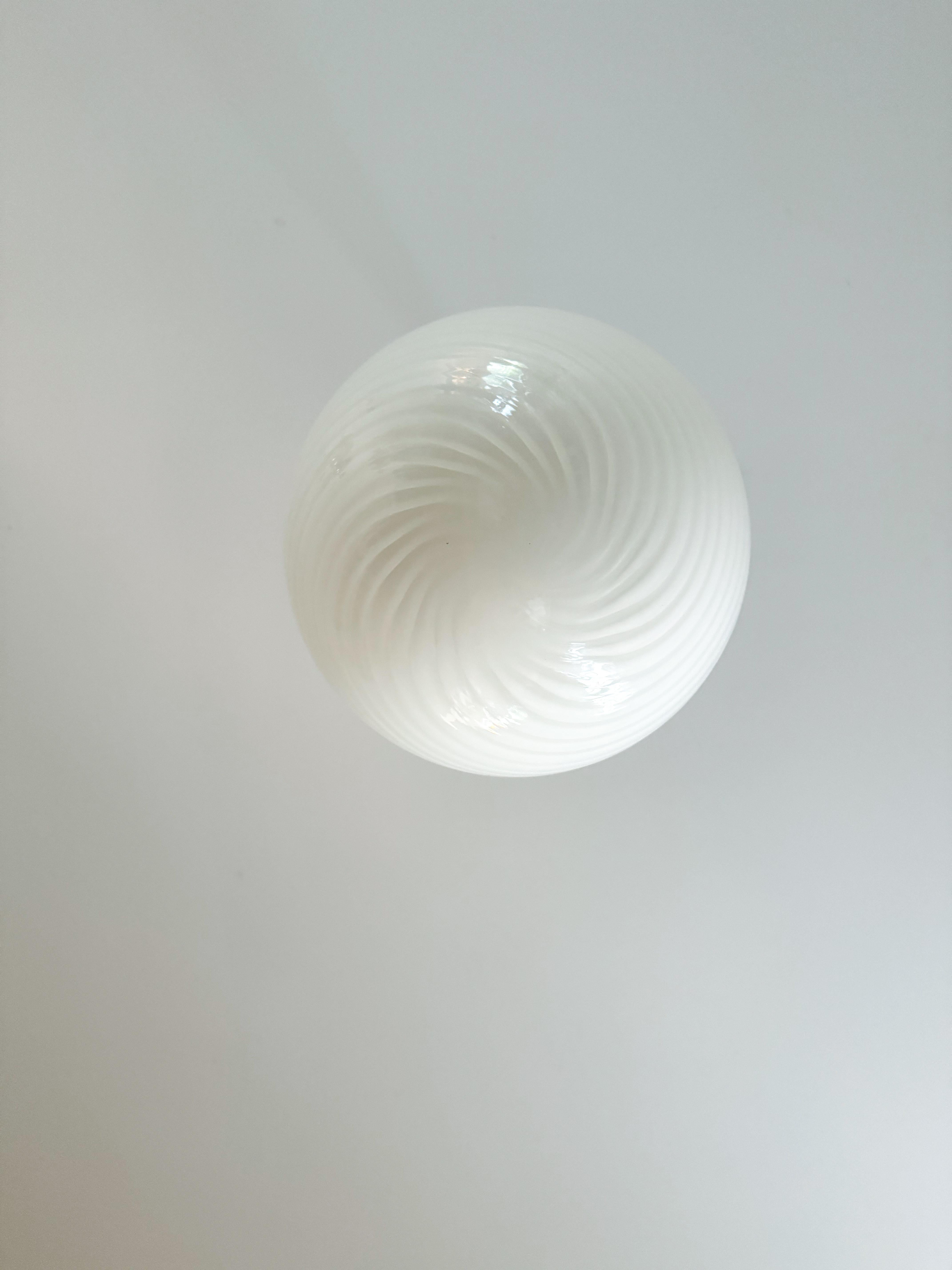 This stunning Murano glass globe pendant lamp, crafted in Italy during the 1970s, embodies the elegance of midcentury design. The handblown white glass sphere features a captivating swirl pattern, showcasing the exceptional craftsmanship of Murano