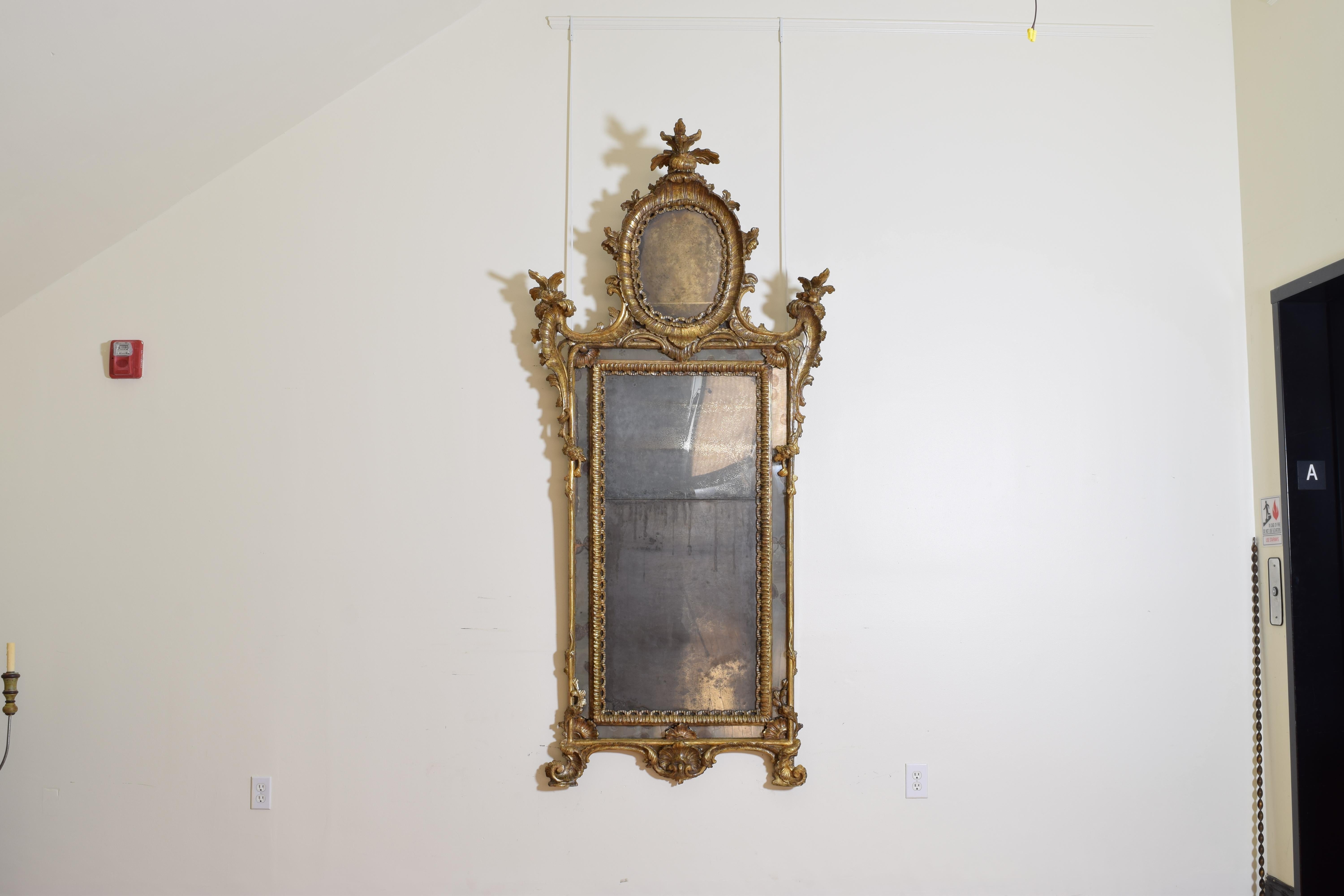 dieser große und bedeutende Spiegel wurde im Rokoko-Stil aus dem frühen 2. Viertel des 18. Jahrhunderts geschnitzt und verziert, er behält seine originalen Spiegelplatten und die Rückwand, das Wort Rokoko ist vom französischen Wort rocaille