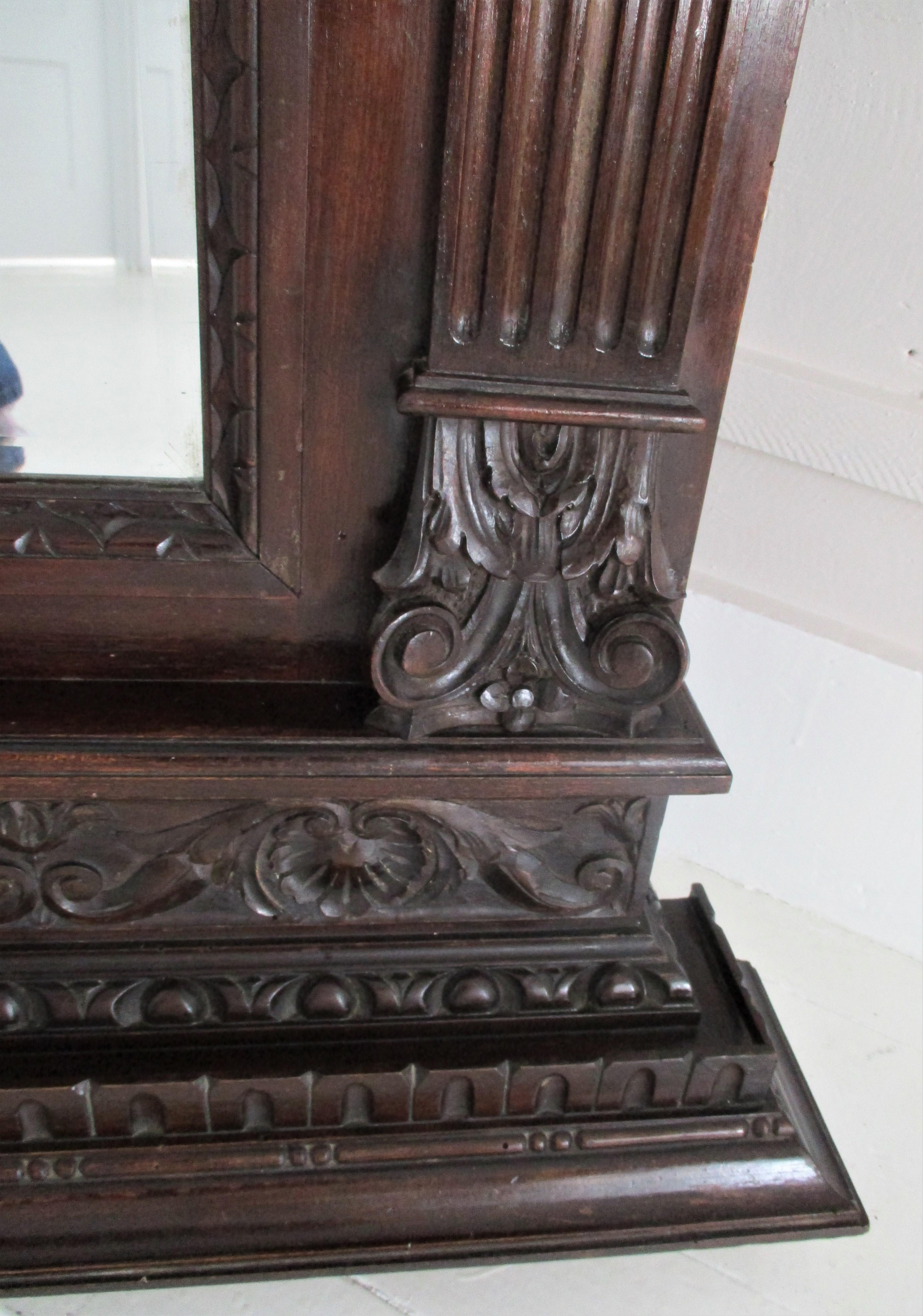 A handsome 19th century neoclassical Italian carved walnut mantel mirror is elegantly carved throughout and comes with a beautiful beveled mirror. This versatile mirror would work great above a fireplace, credenza, commode, buffet or console
