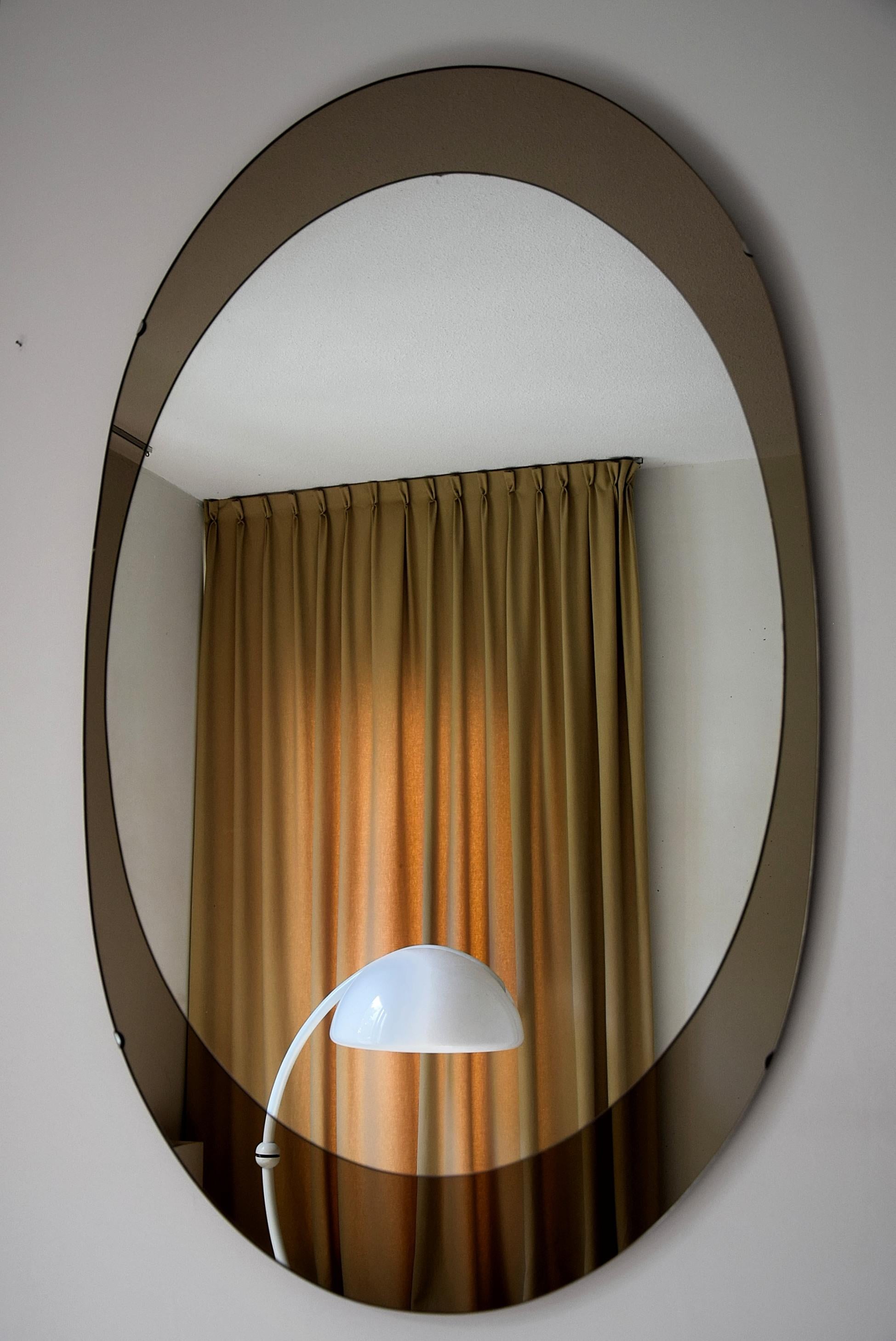 Impressive and stylish oval mirror with stylish bronze mirrored frame produced by Cristal Arte, Italy in the 1960s.
This beauty measures 132 cm or 4.4 feet x 80 cm or 2.8 feet. It can be hung either vertical or horizontal as can be seen in the
