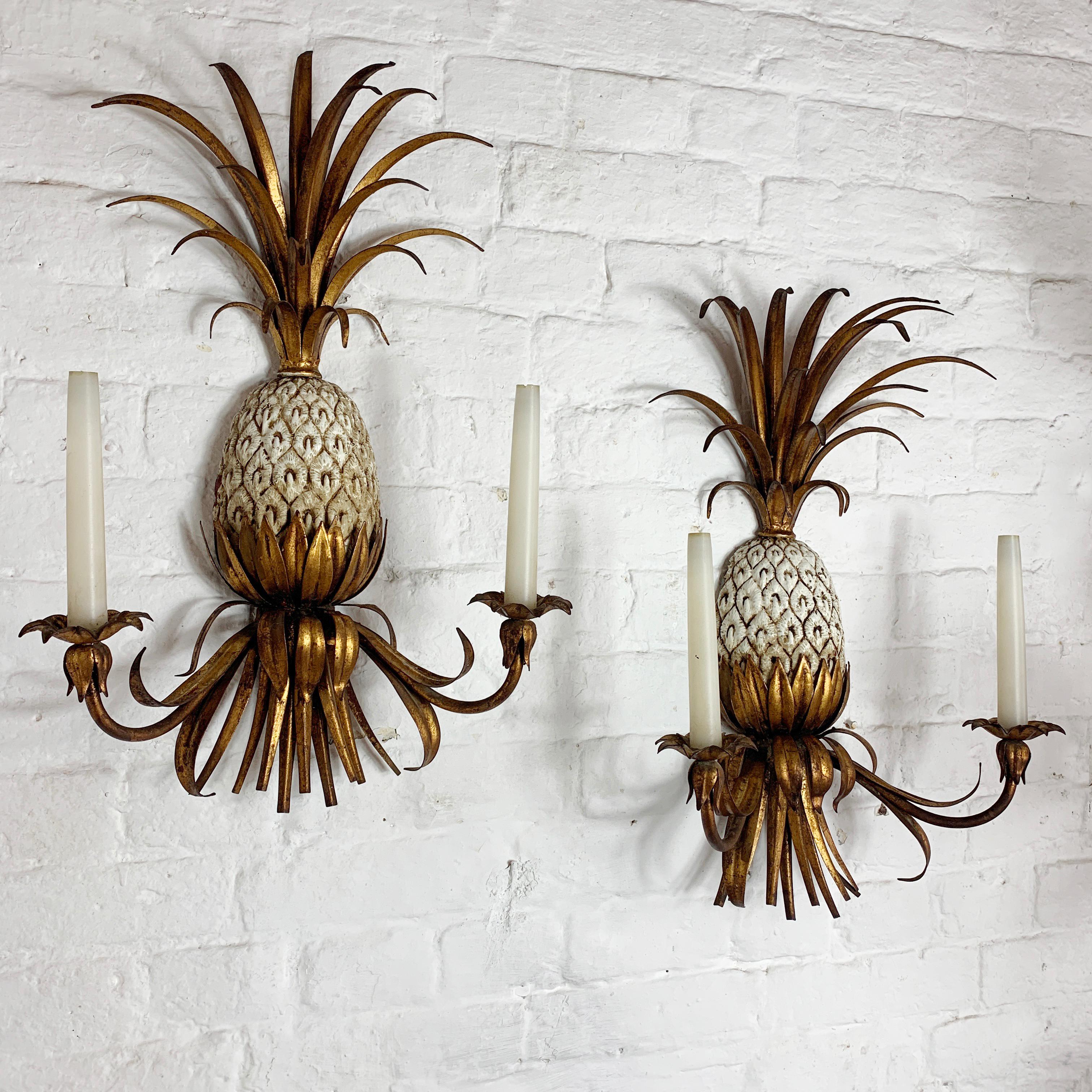 Stunning pair of gilt tole ware pineapple wall sconce's
Italian
circa 1950s-1960s
The central pineapple is metal and in cream color with gold highlights
The fronds are large and full
The lights have 2 bulb holders each, they take a small E10