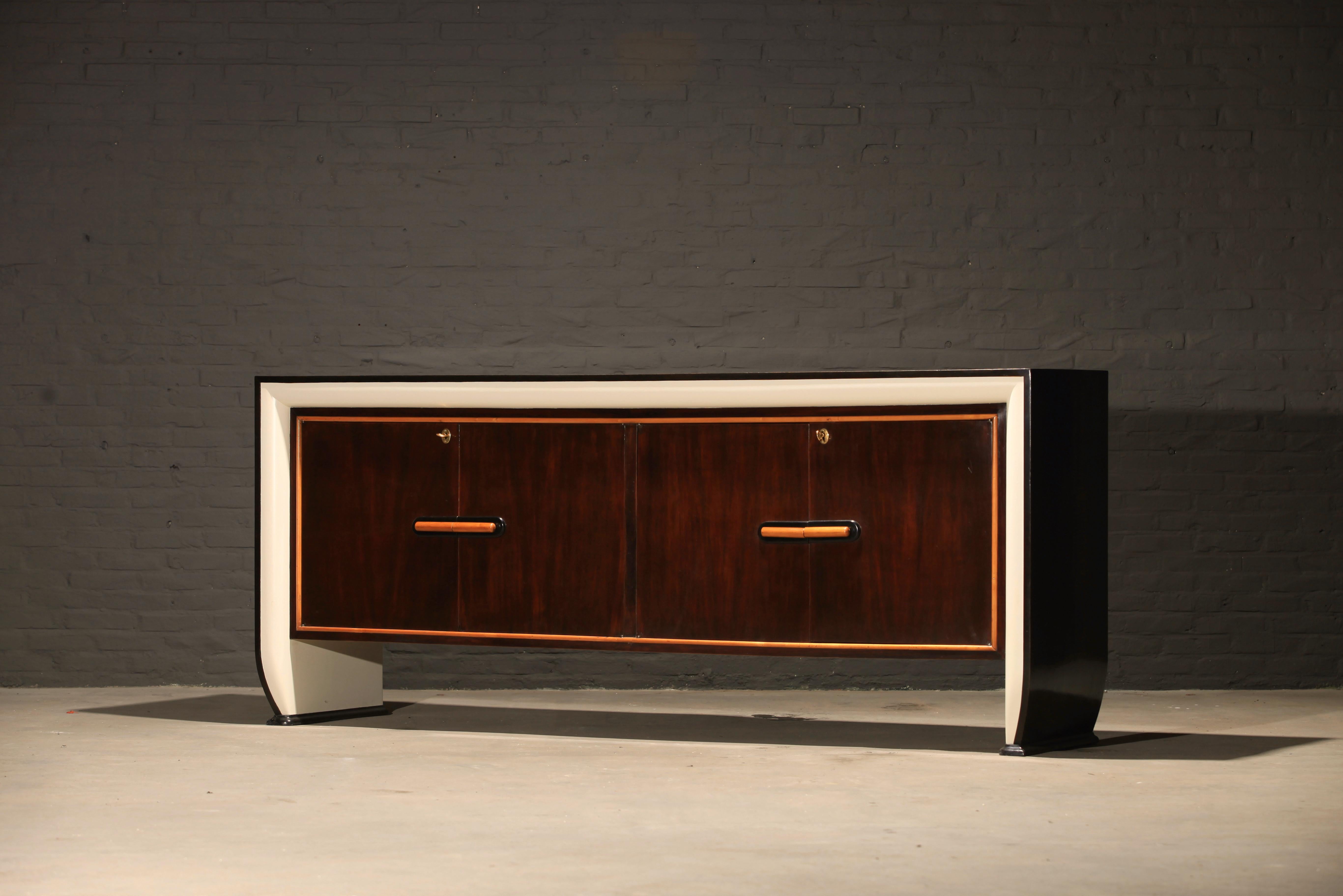 Impressive large sideboard attributed to the Italian designer Osvaldo Borsani. The use of different types of wood such as lime, beech, mahogany, black and ivory lacquered wood in combination with the smooth shaped legs are distinctive for the way