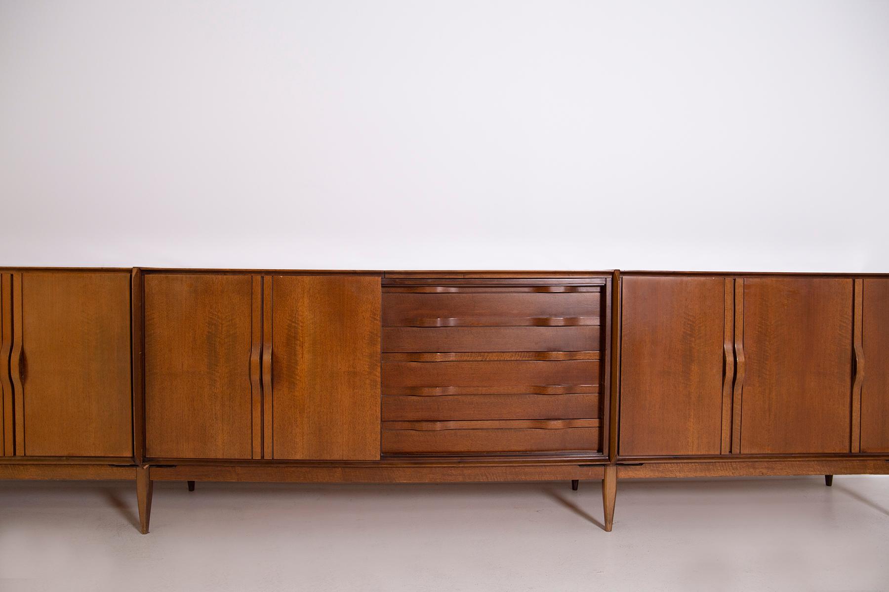 Large Italian sideboard from the 1950s made entirely of walnut. The large Italian sideboard is made in many compartments. It has two single side doors, three double central doors and inserted in the middle a small chest of drawers with 4 drawers.
