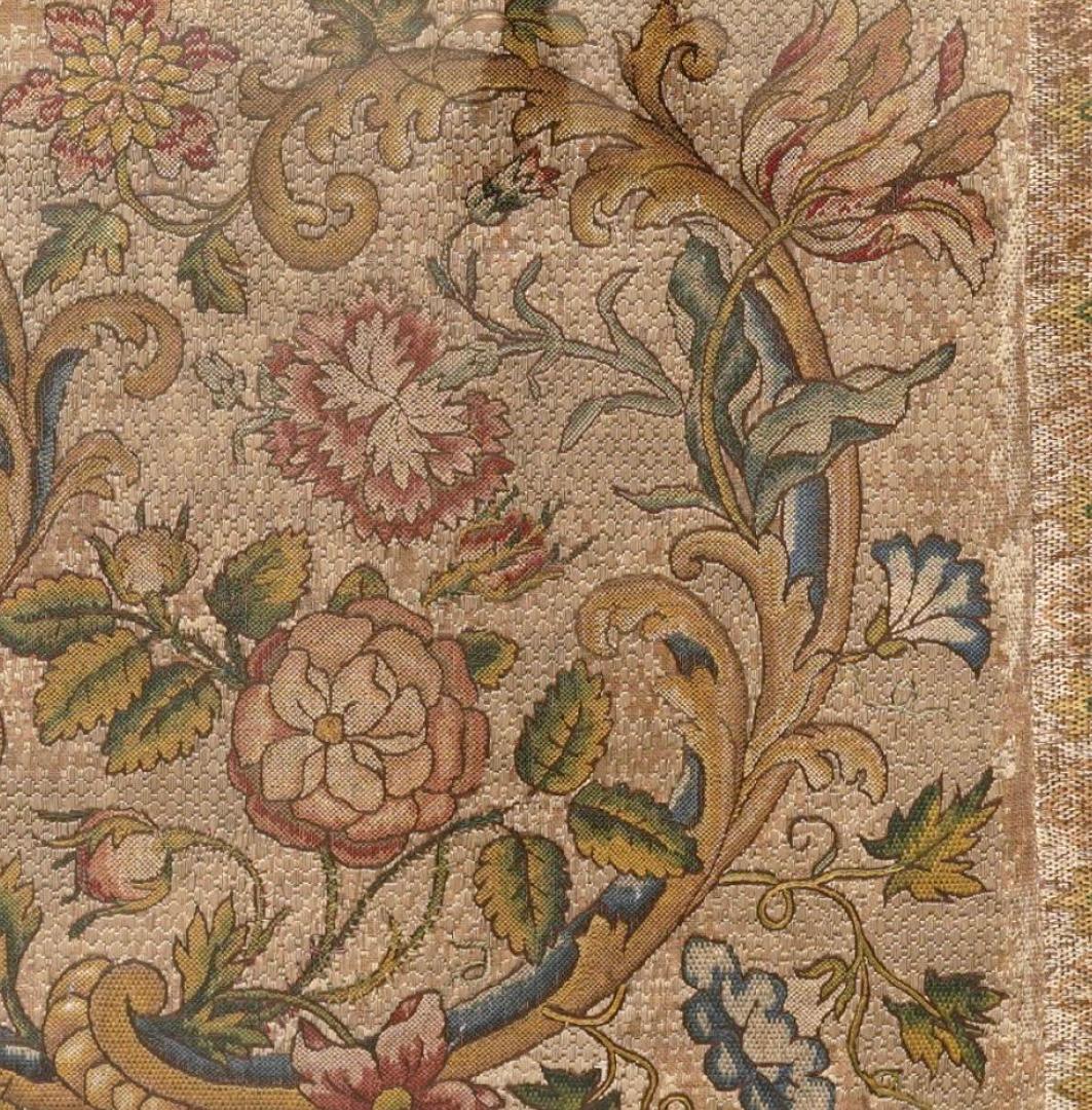 Panneau textile de broderie de soie italienne encadré, datant du 18e siècle. Le textile présente un motif symétrique finement équilibré de vignes d'acanthe enroulées et d'abondantes fleurs épanouies dans des tons doux de rose, de bleu, de vert et