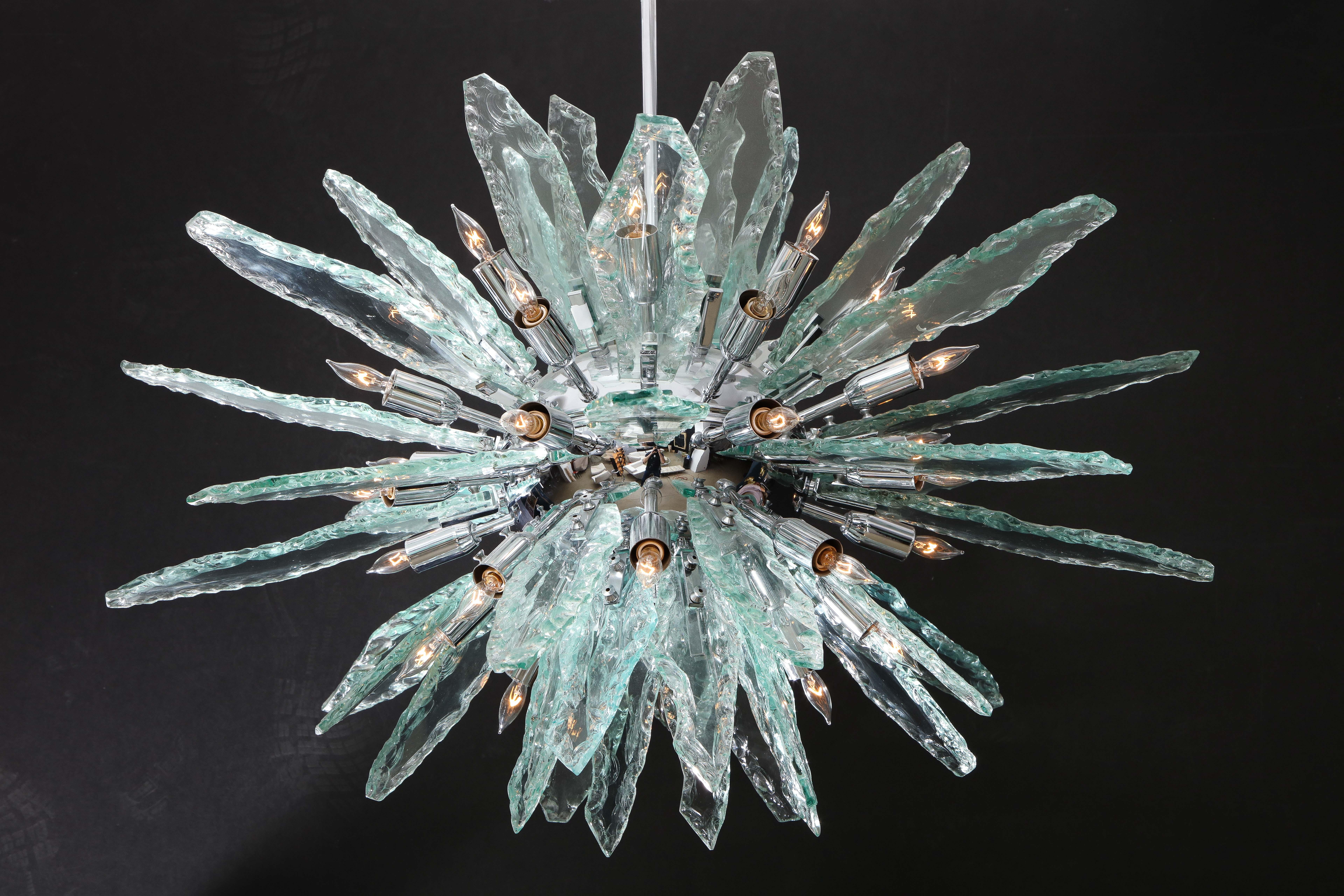 Large Italian Sputnik chandelier in the style of Fontana Arte consisting of six rows of thick, flat, jagged edge hand blown clear glass slabs that screw into a chrome 34 inch diameter frame with 26 sockets accommodating candelabra bulbs, suspended