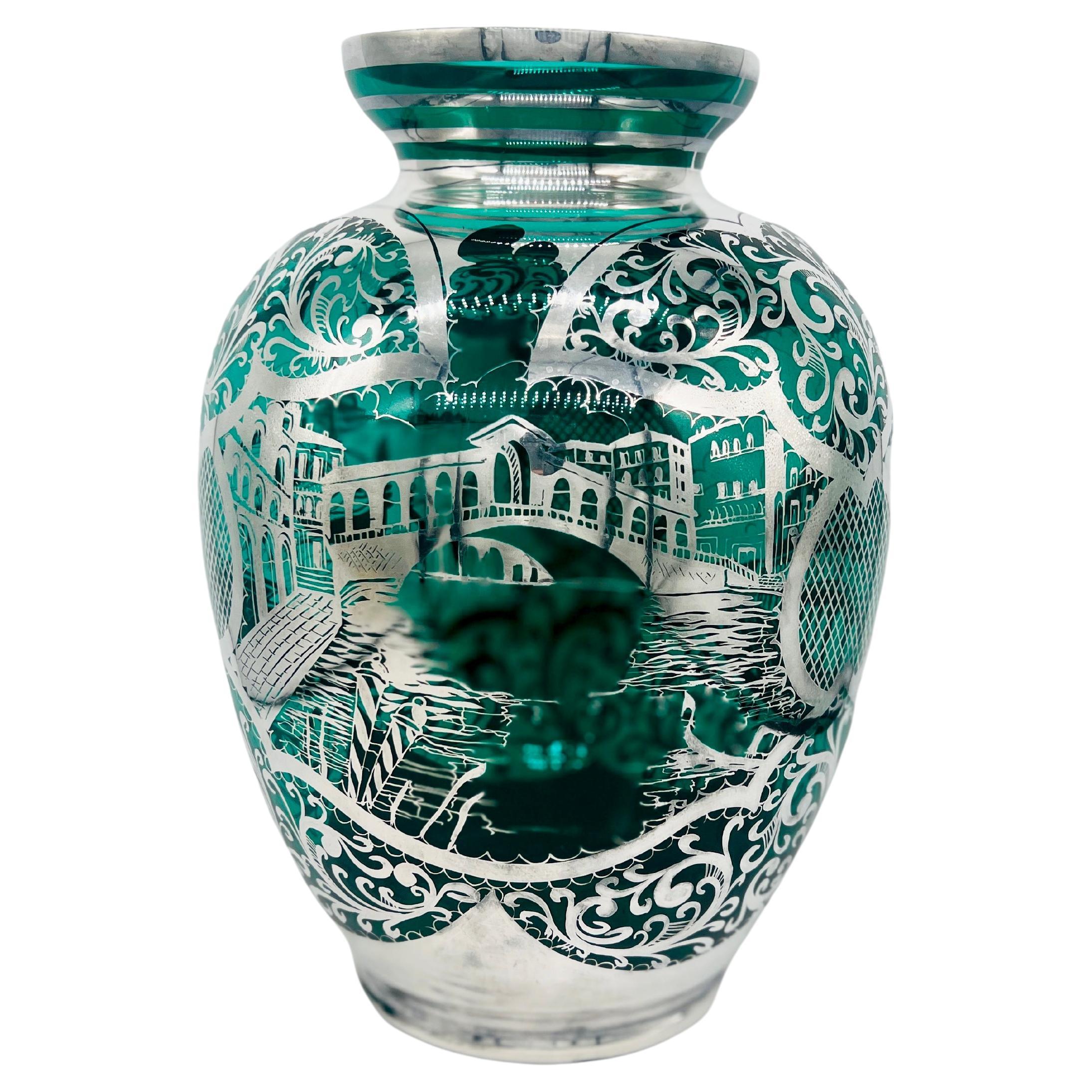 Italienische Handwerkskunst und venezianische Kunstfertigkeit. Die Vase besteht aus leuchtend grünem Glas, das mit einer aufwendigen Sterlingsilberauflage veredelt ist, die eine kunstvolle venezianische Szene darstellt. Das Overlay enthält
