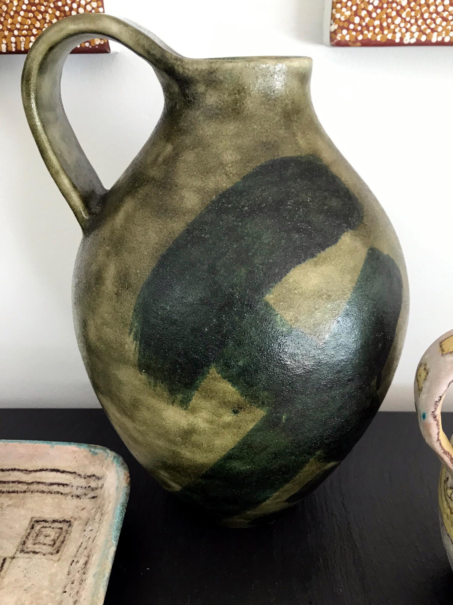 An impressive and large stoneware pitcher by Guido Gambone, Italy, circa 1960s. In a mottled green glaze with darker strokes. The abstract geometrical decoration contrasts the Classic organic form. A bespoken and timeless piece from Guido Gambone.