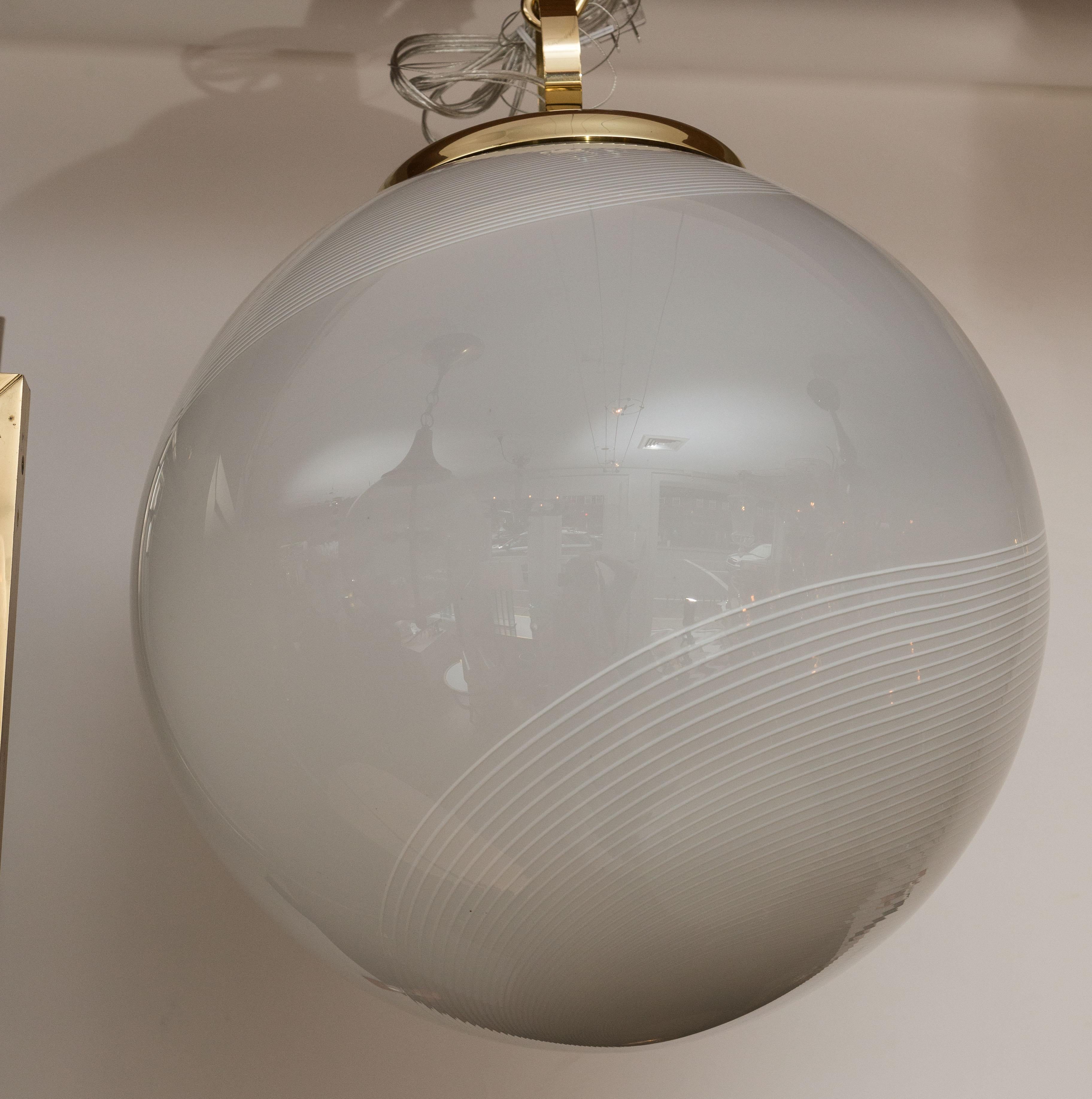 Grande globo soffiato in stile moderno di colore bianco sporco, ornato da volute di filigrana bianca, sorretto da una cornice originale in ottone lucidato e non laccato con un grazioso anello rotondo.
Origine: Murano, Italia
Datazione: