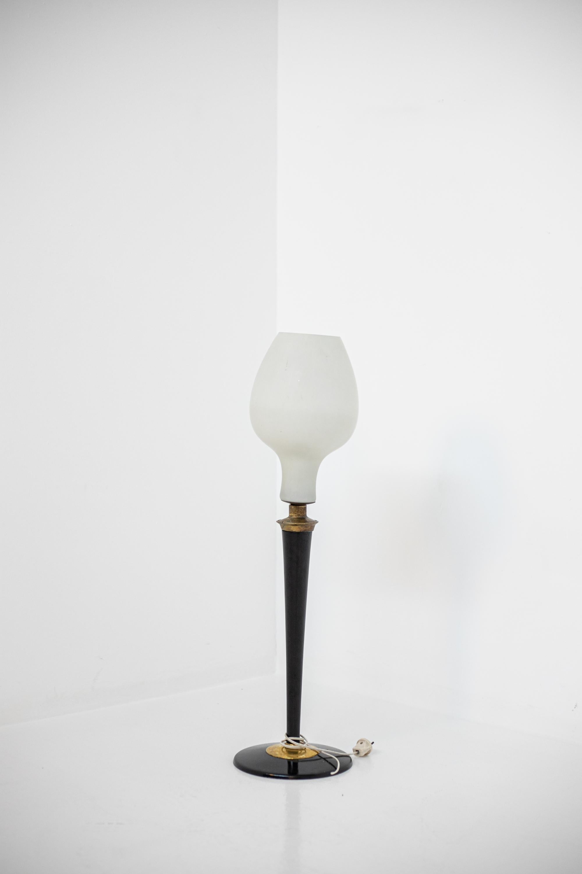 Grande lampe de table italienne des années 1950. La lampe a un couvercle en verre opale de forme ovale avec une seule lumière centrale. La lampe a une structure en bois peint avec des inserts en laiton. La base de forme circulaire confère stabilité