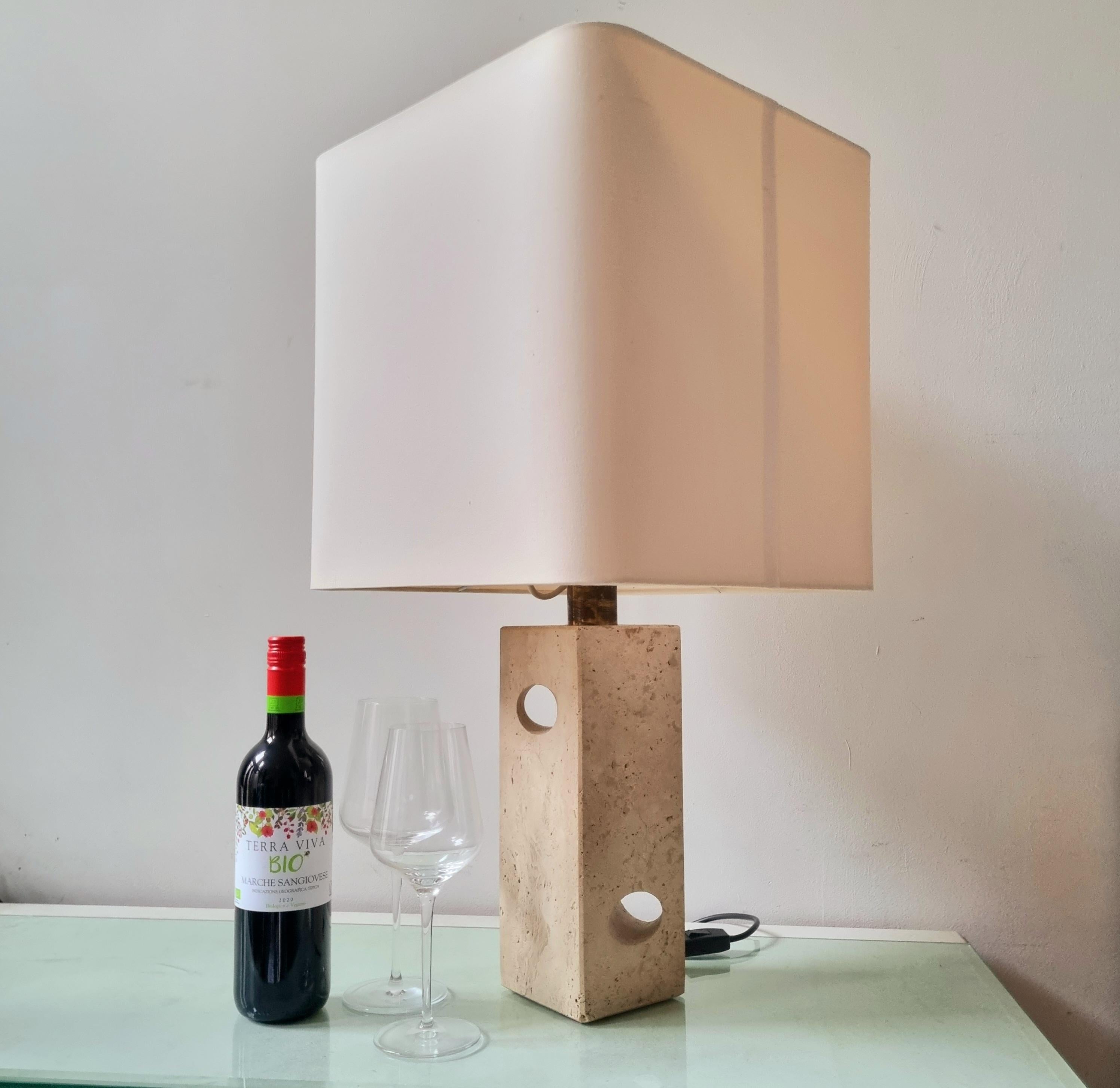 Circa 1970. A very elegant and heavy table lamp by Fratelli Mannelli or in the style of, the renowned Italian designer of travertine objects. It features a sculptural travertine base, brass plated lamp holder and an off-white fabric shade. The lamp