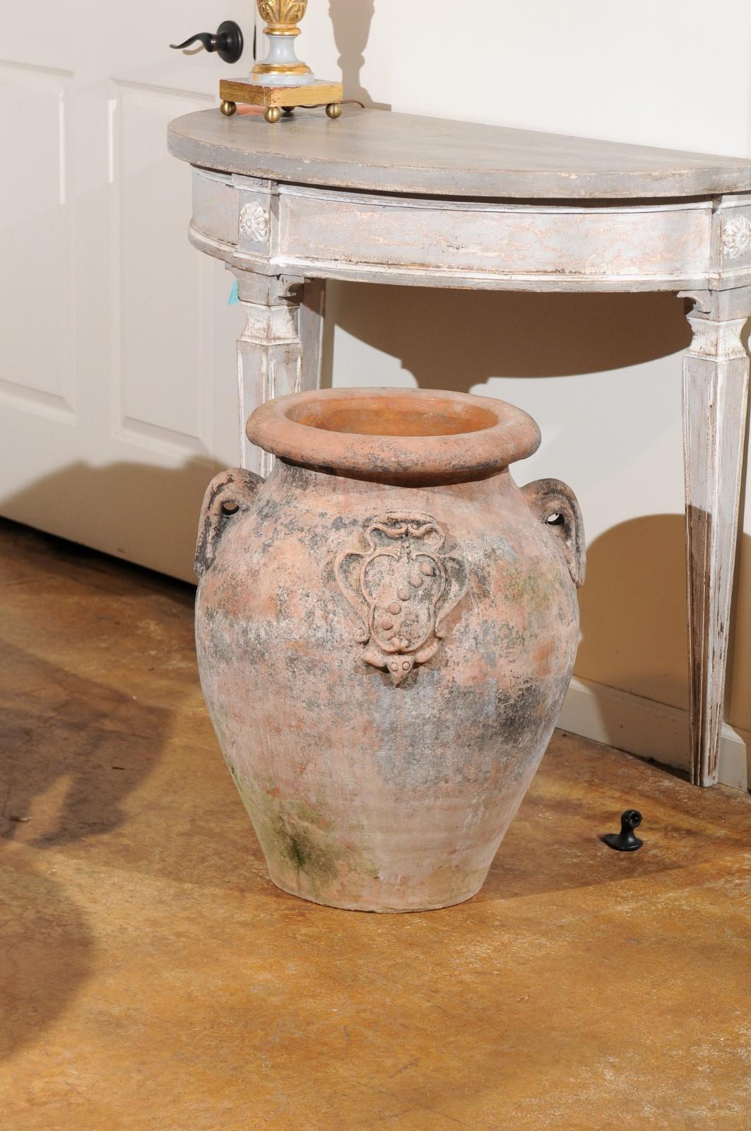 A large Italian terracotta jardinière from the 20th century with double handles and family heraldic crest. Born in Italy during the 20th century, this Italian olive jar jardinière features a large lip leading our eye to the rounded belly of the