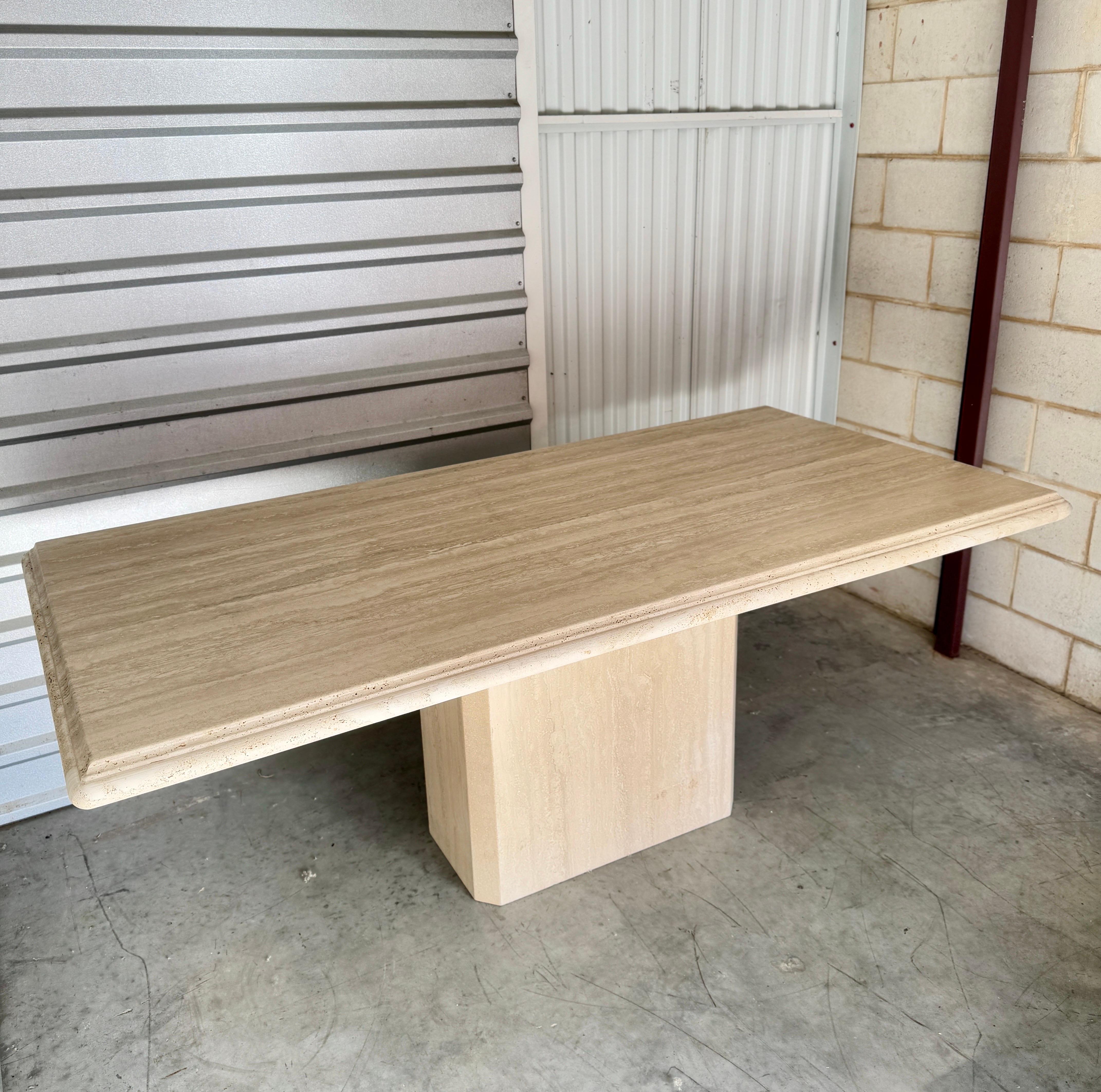 This Large Travertine Beveled Edge Single Pedestal Rectangle Dining Conference Table is a statement of timeless elegance. Crafted with meticulous attention to detail, the table boasts a stunning travertine stone top with finely beveled edges. The
