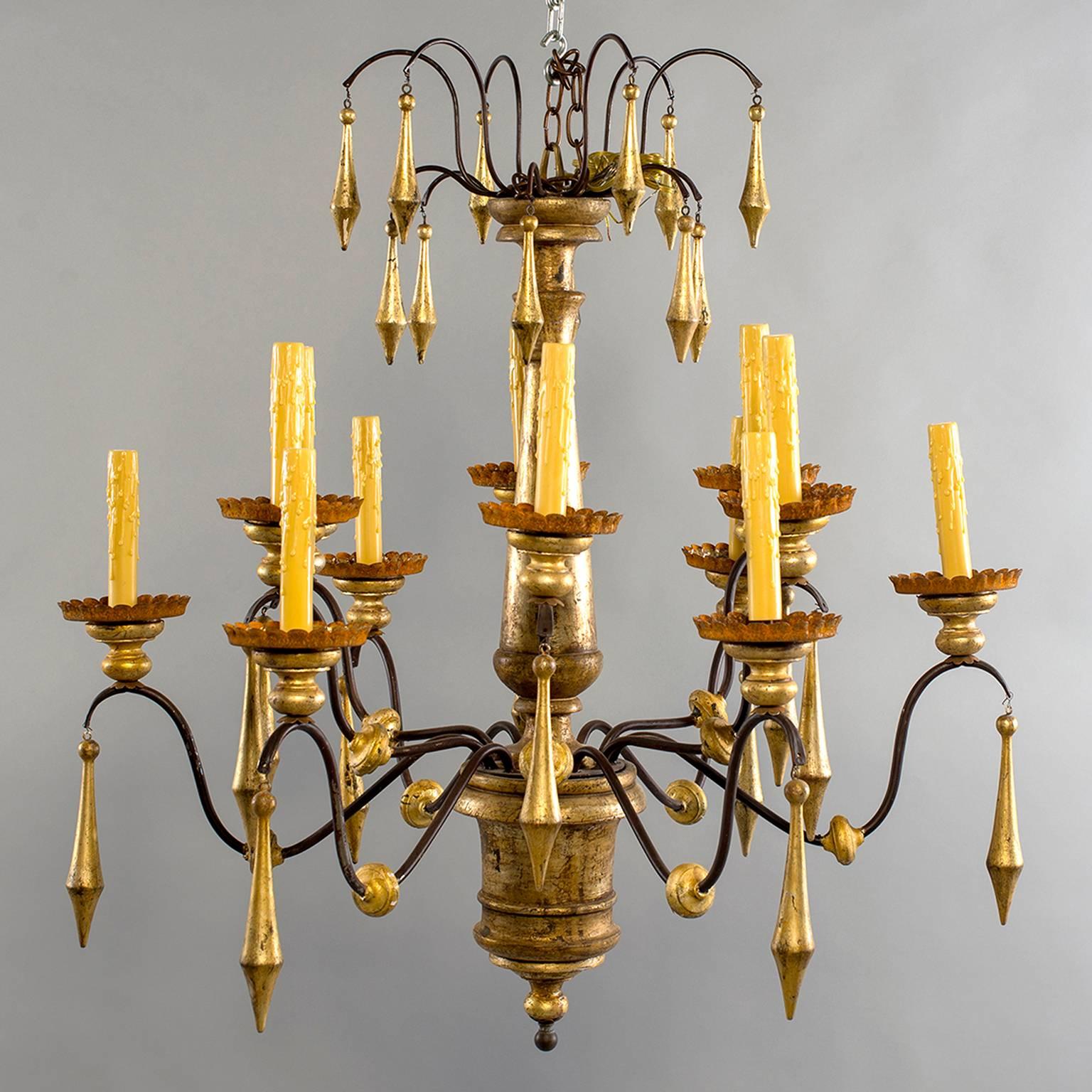 Large Italian gilded wood and iron chandelier with 12 candle style lights and two tiers of large dangling giltwood pendants.
# of Sockets: 12
Socket Type: Candelabra.