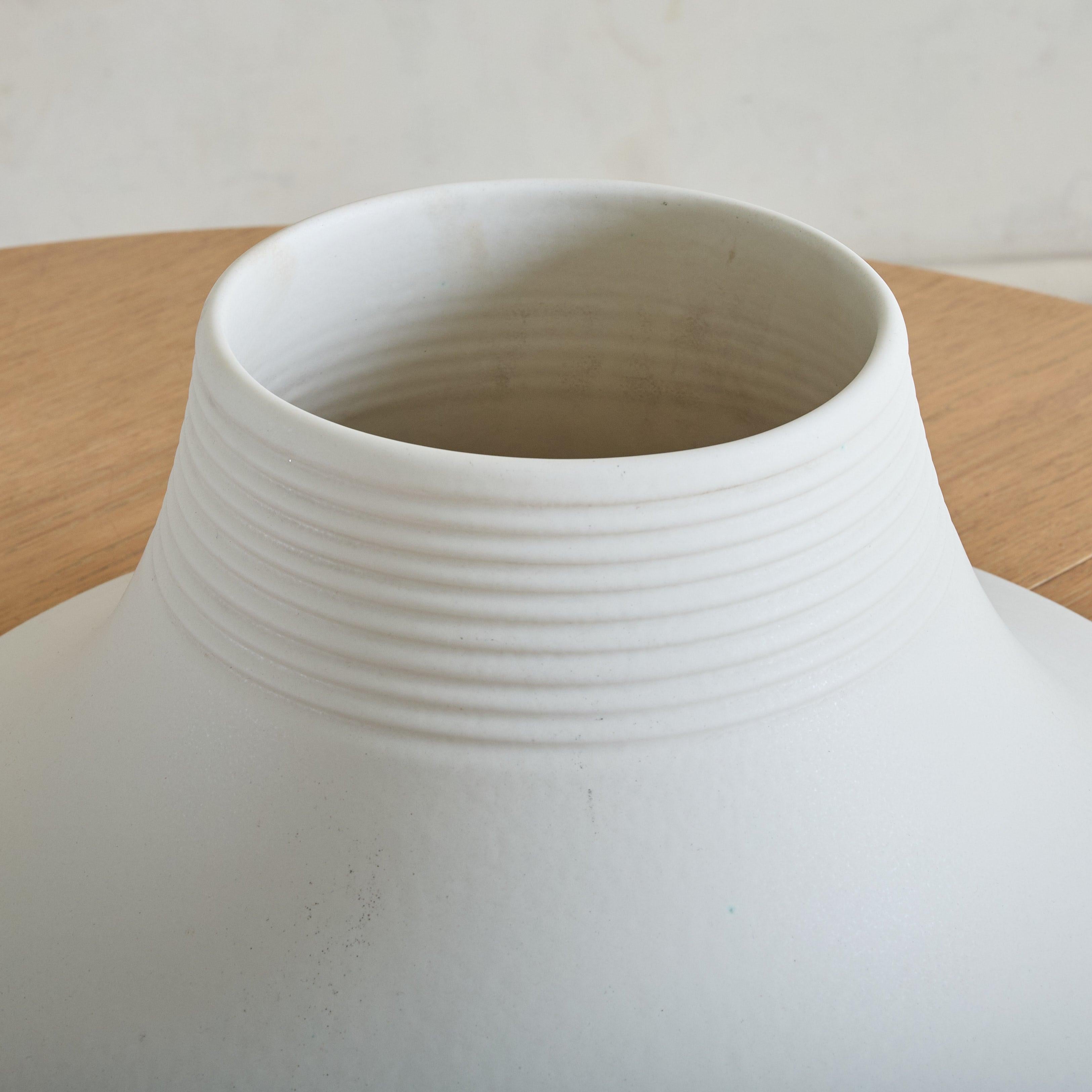 A rare ‘Vesuvio’ vase designed by Angelo Mangiarotti for Gabbianelli in the 1970s. Its modernist, truncated silhouette flares outward in a dramatic gesture, softened by a delicately ribbed neck and recessed base. Crafted in matte white ceramic, the