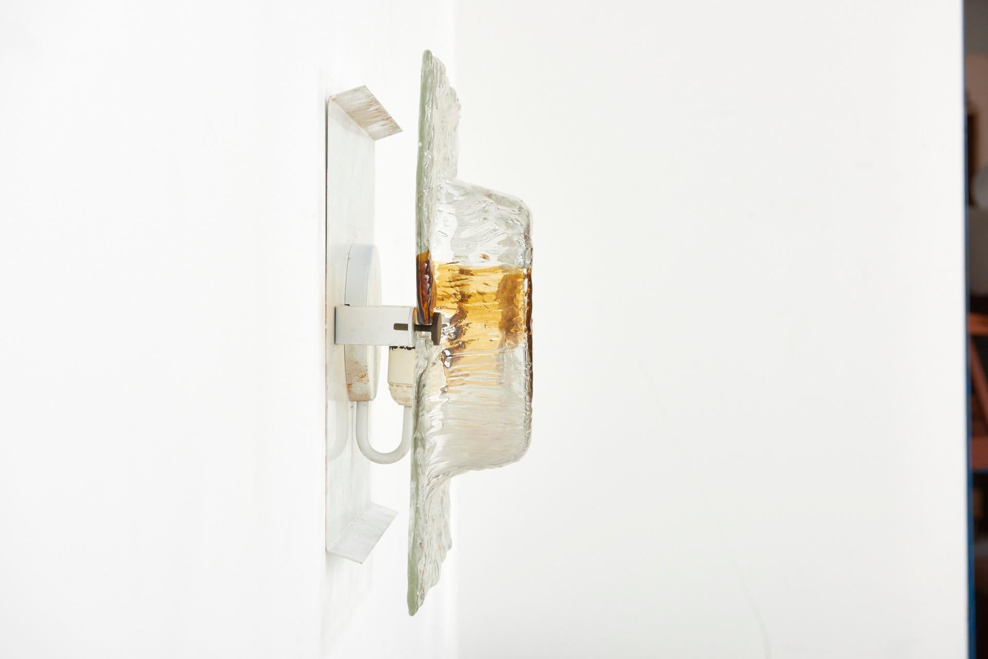 This large Italian wall lamp was designed by Toni Zuccheri for Venini in the 1960s. It features handblown Murano glass with amber tones, white lacquered frames, brass screws, and a Bakelite socket.