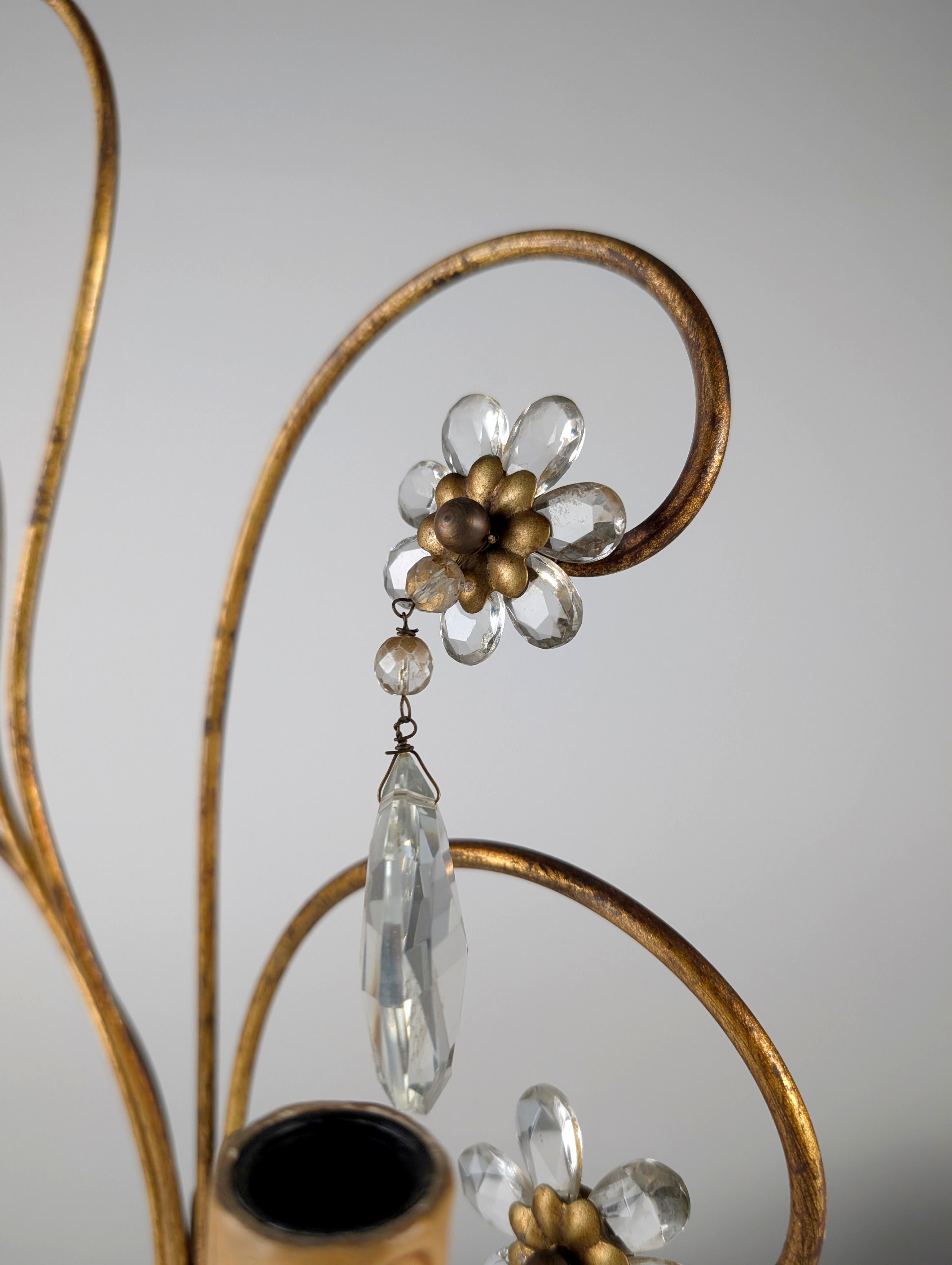 Elegant mid-century Italian wall sconce crafted in gilt metal and cut crystal, inspired by the most refined designs of Maison Baguès. Featuring a floral composition with gracefully ascending curves and naturalistic decorative elements, this sconce