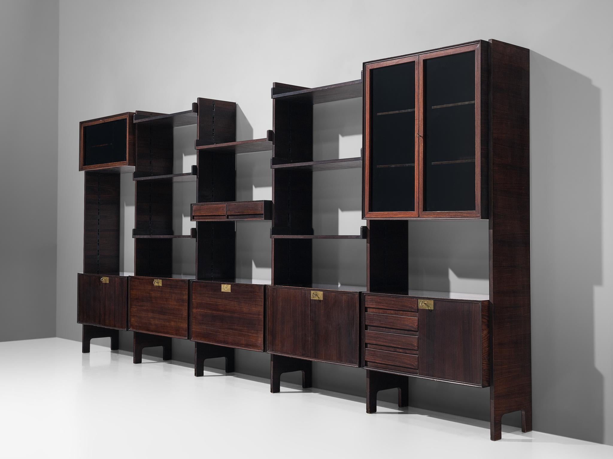 Wall unit with cabinets, rosewood and brass, Italy, 1960s. 

The monumental wall-mounted wall unit with cabinets consists of five wall sections with various different storage facilities. Each section with shelves is built up from a cabinet with