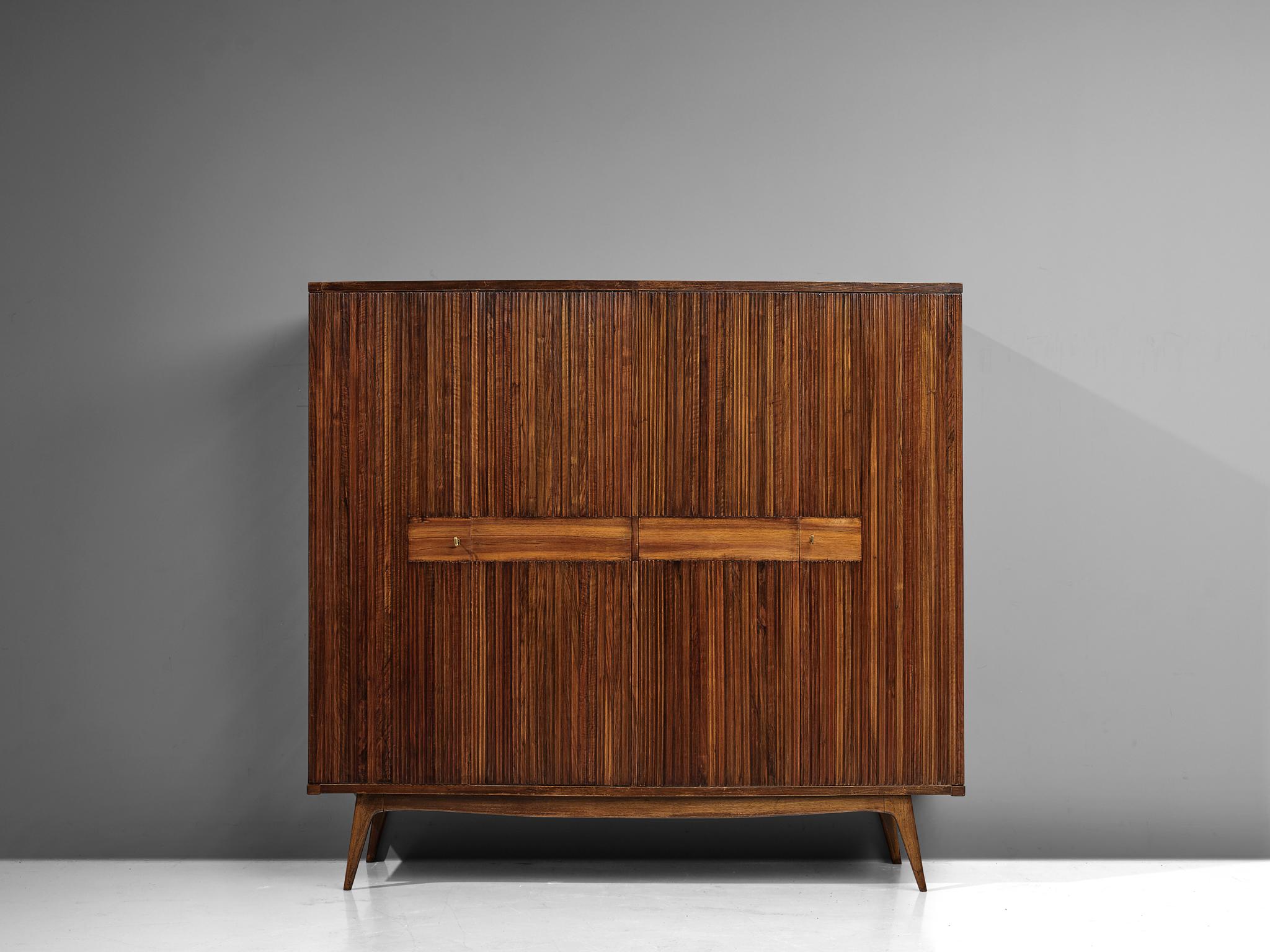 Large wardrobe, walnut, brass, Italy, 1960s

This truly elegant Italian wardrobe has a striking design. Not only the relief surface of the front doors but also the solution of the base is a convincing combination. The tapered and slanted legs lift