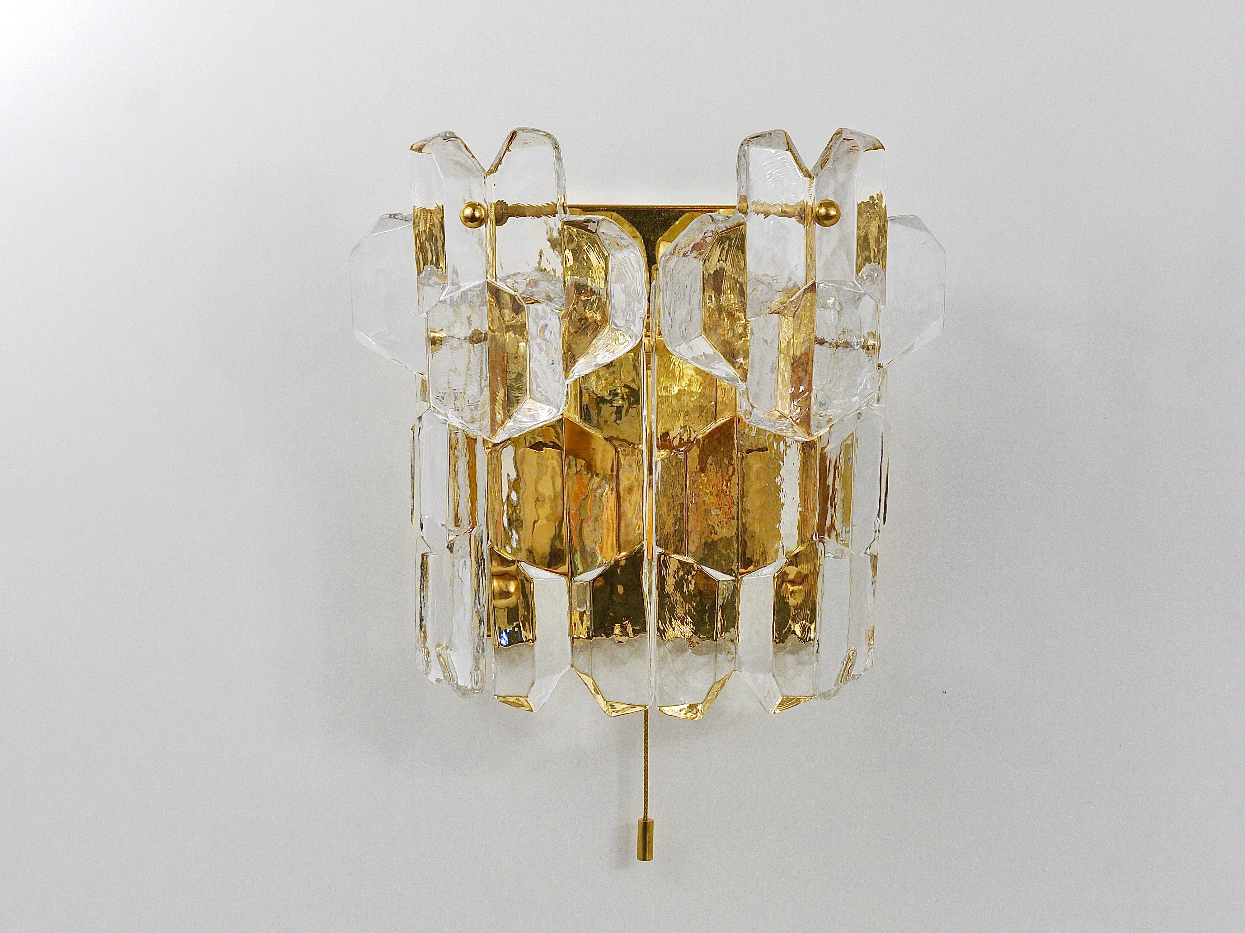 An elegant and large handmade wall light, produced by Kalmar Franken KG in the 1970s. Its frame is made of gold-plated brass and it has two layers of solid polished ice glass crystal glasses. The wall light offers three lights sources and has an