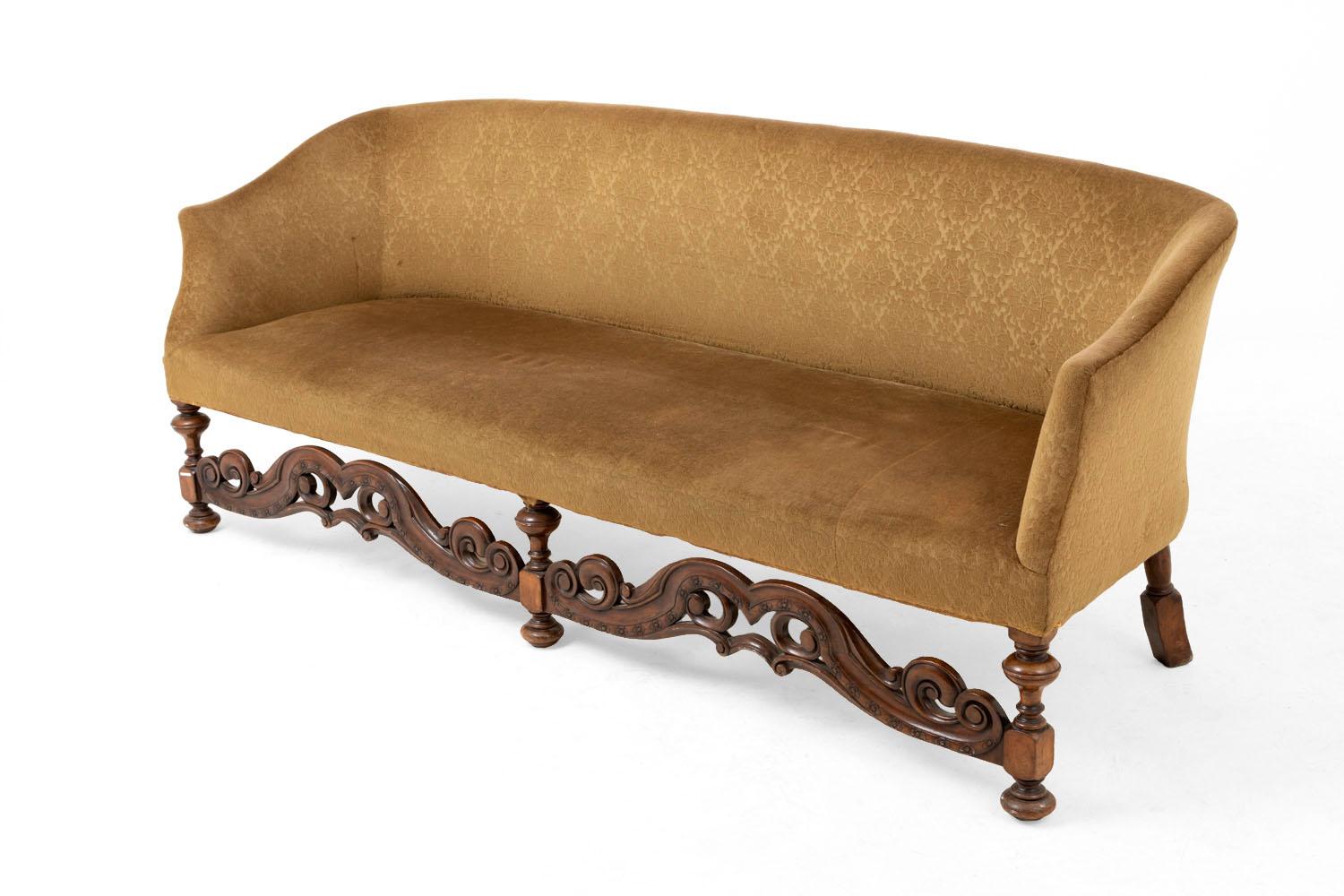Large Jacobean English style sofa in carved and turned walnut standing on five moulded legs : the three front legs are in turning in bun and back legs have a superior part in column shape and inferior part in rectangular shape. Front legs are linked