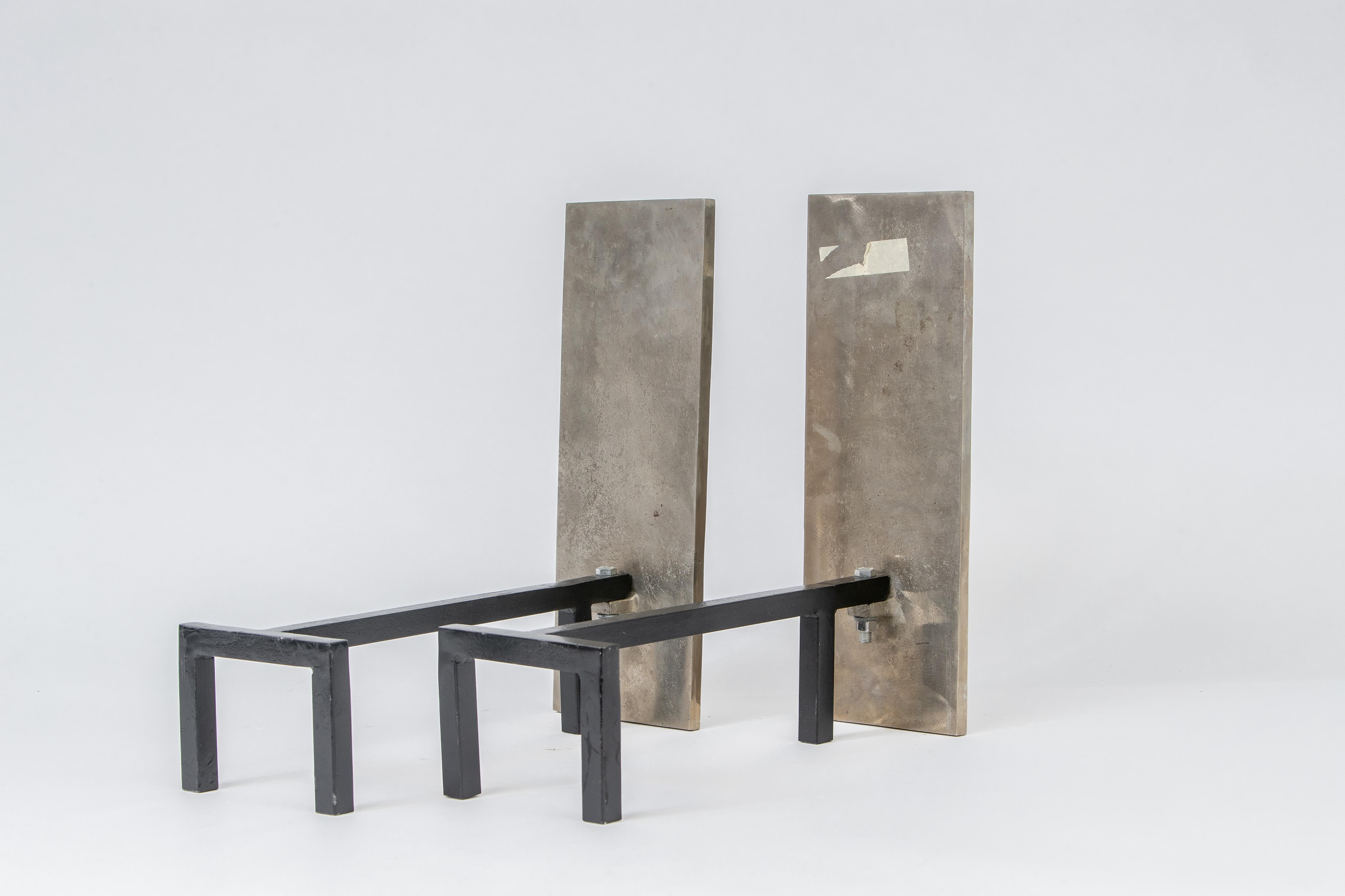 A large pair of modernist andirons in nickel-plated bronze by Jacques Adnet. The front is a large slab of bronze finished in nickel with nice aging. A robust design.