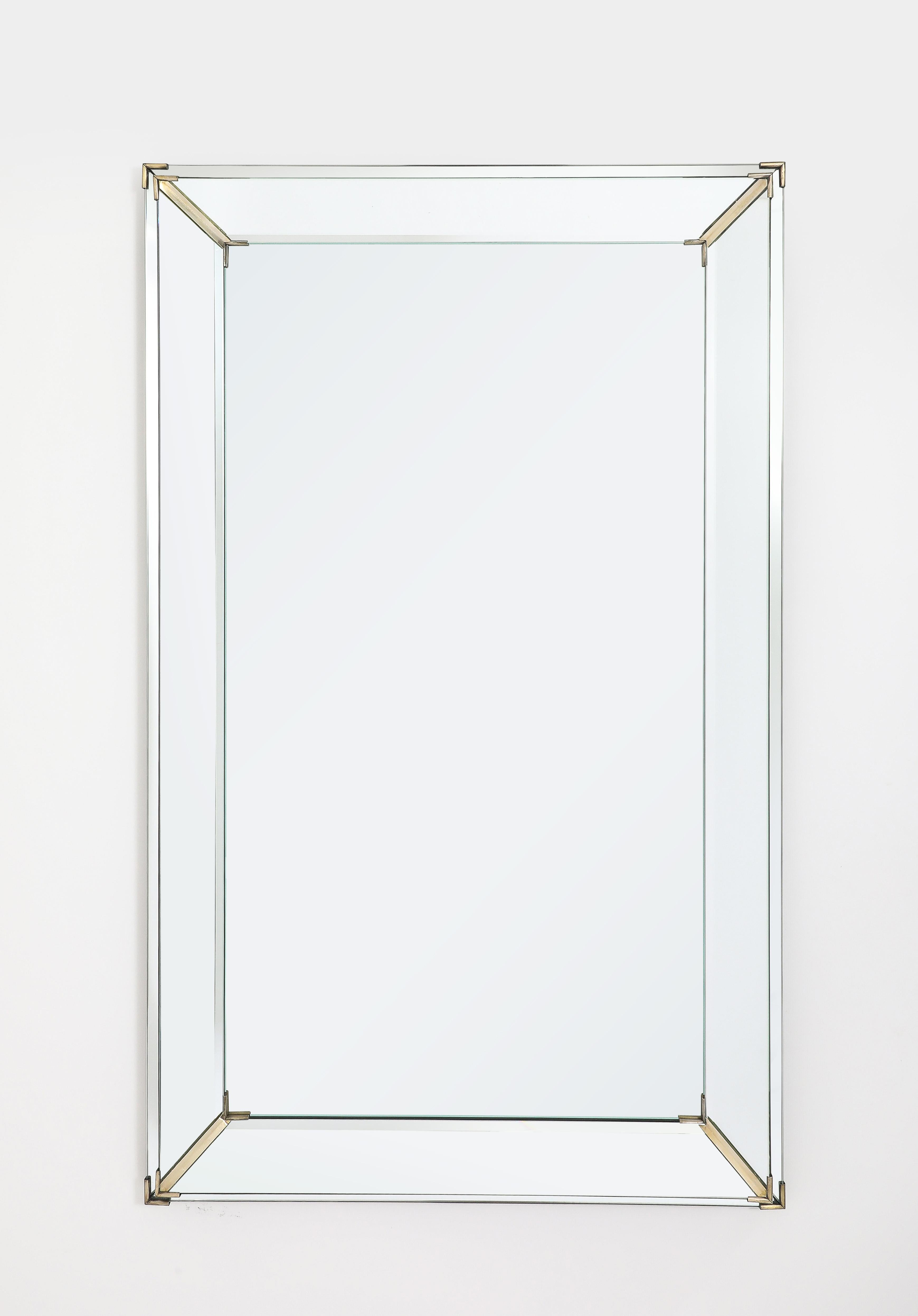 Un grande specchio a gradini con accenti in ottone argentato su una cornice in noce.
