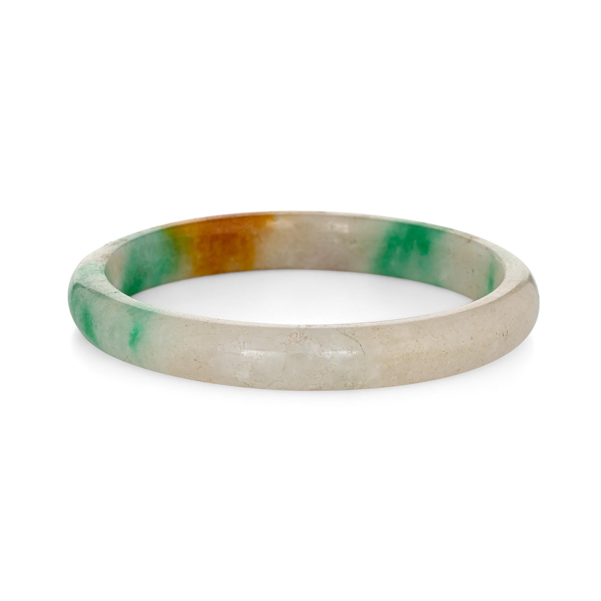Jadeite jade bangle bracelet. 

The jade bracelet measures 11.5mm wide (0.45 inches).      

The jade graduates in color from green to orange and white. The bracelet is large in size and is designed to slip over the wrist (inner diameter is 2.75