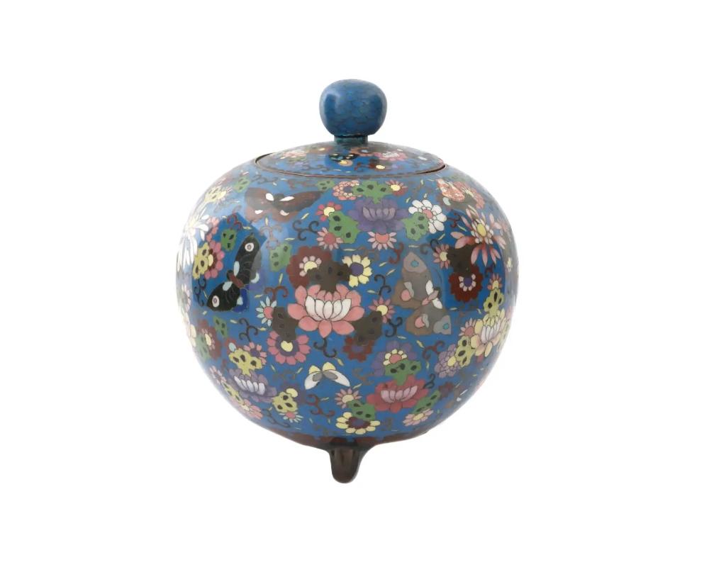 A large antique Japanese cloisonne enamel jar and cover, late Meiji period. The jar is of a spherical form, decorated with polychrome patterns depicting butterflies flying among chrysanthemums and other flowers on a dark turquoise ground, the bottom