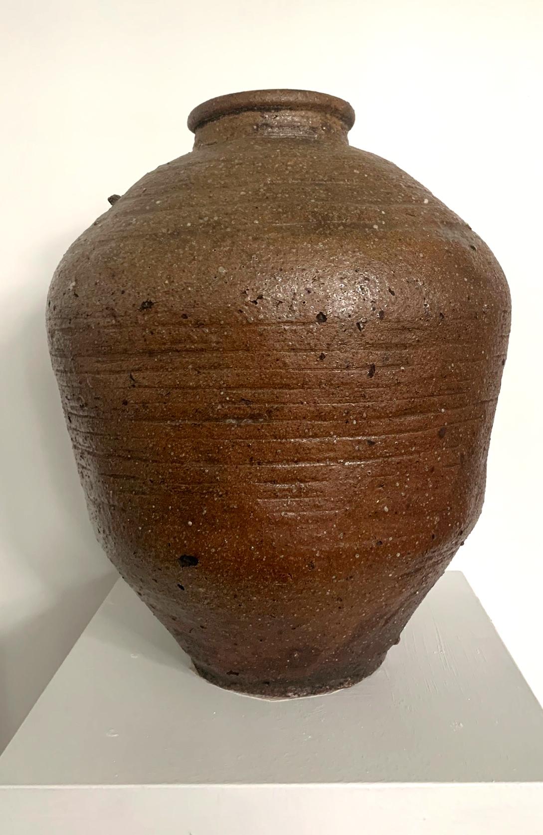 An antique Japanese stoneware storage jar, known as tsubo from Shigaraki kiln, circa 17th-18th century (early Edo possibly Momoyama period). The tsubo is of an impressive size at nearly 20 inches high, hand-built with the sandy clay from the local