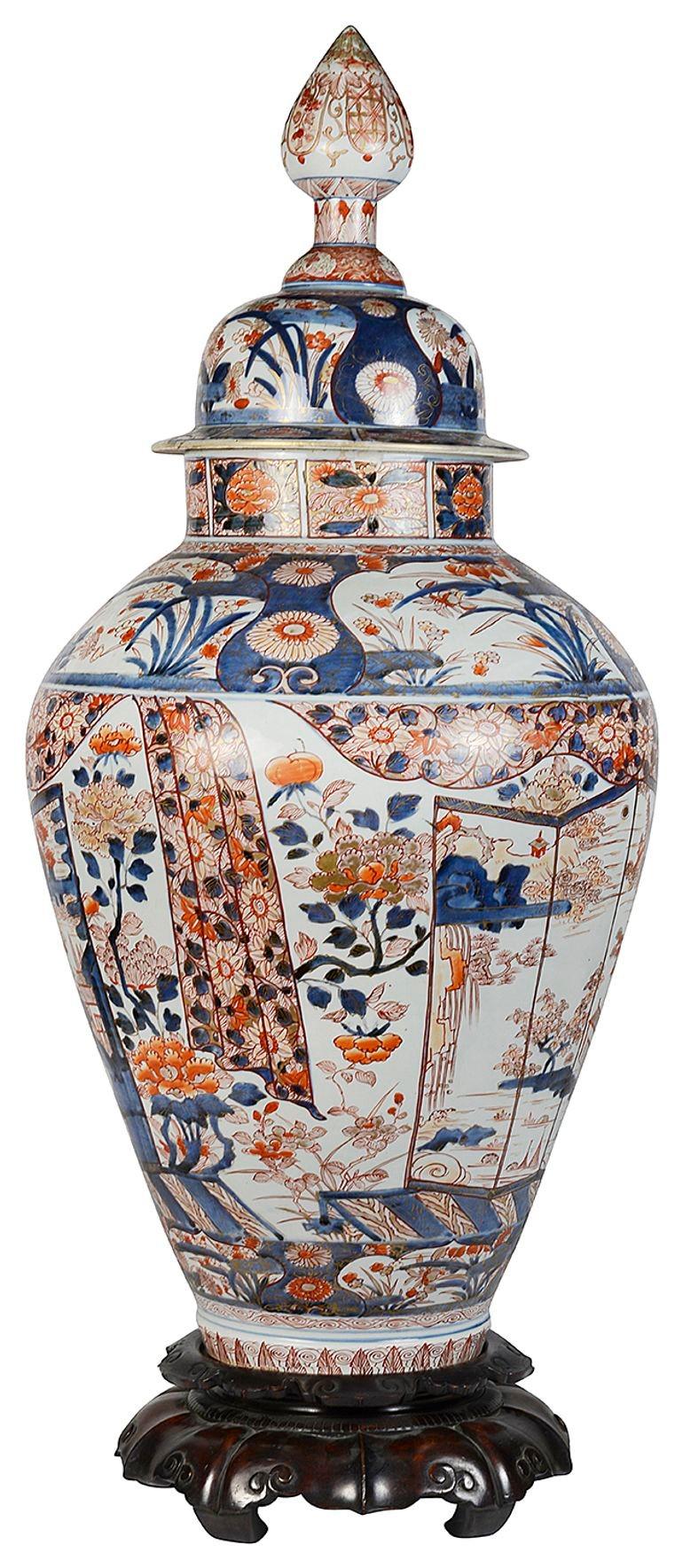 This wonderful large 18th Century Japanese Arita Imari lidded vase on stand. Having boarders of classical motif and foliate decoration, inset hand painted panels exotic plants and flowers, also a four fold screen with a lake and buildings. Mounted
