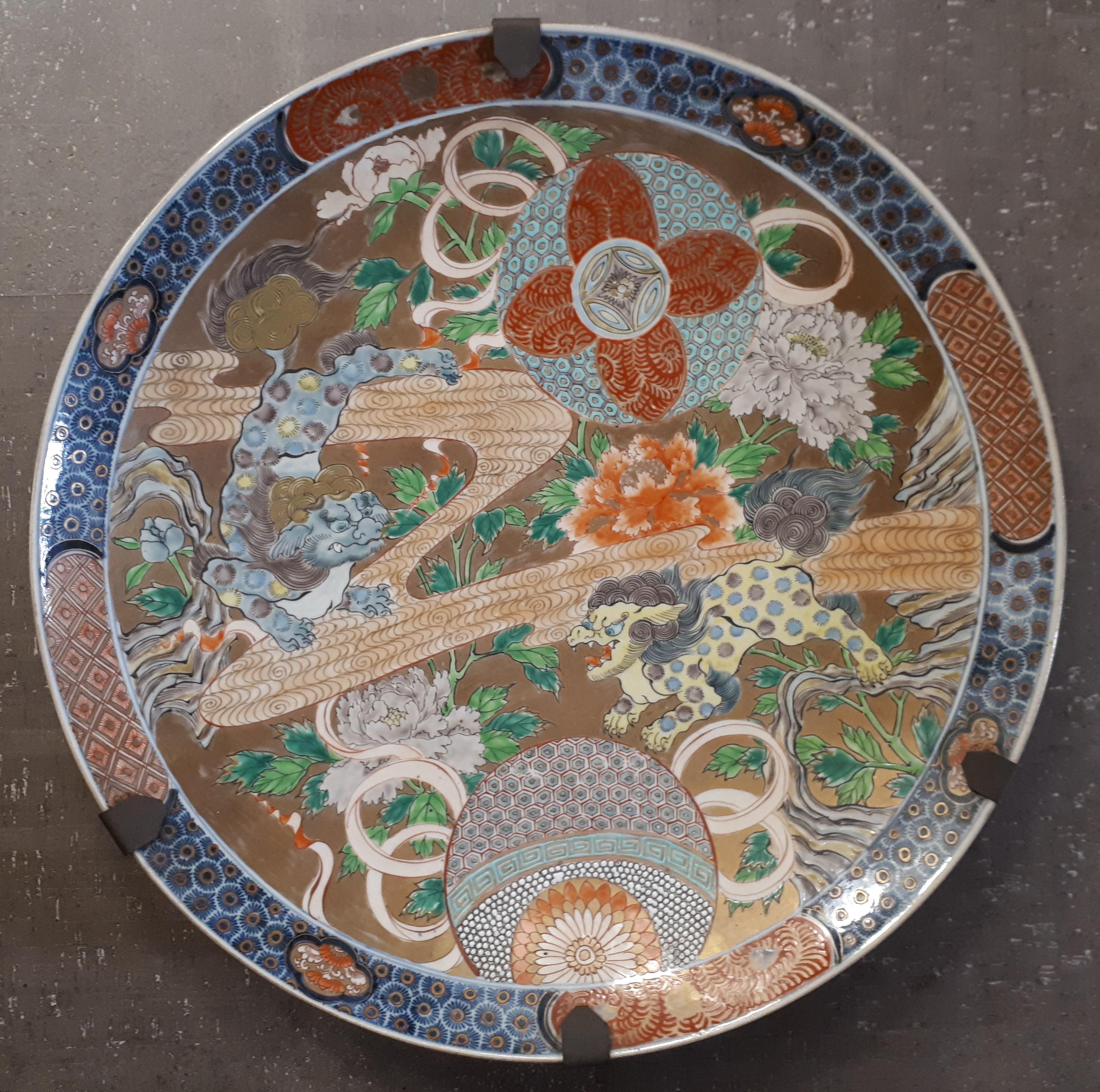 A large Arita porcelain dish with polychrome decoration on a gold background of shishi among peonies.
Japan, late 19th century.
