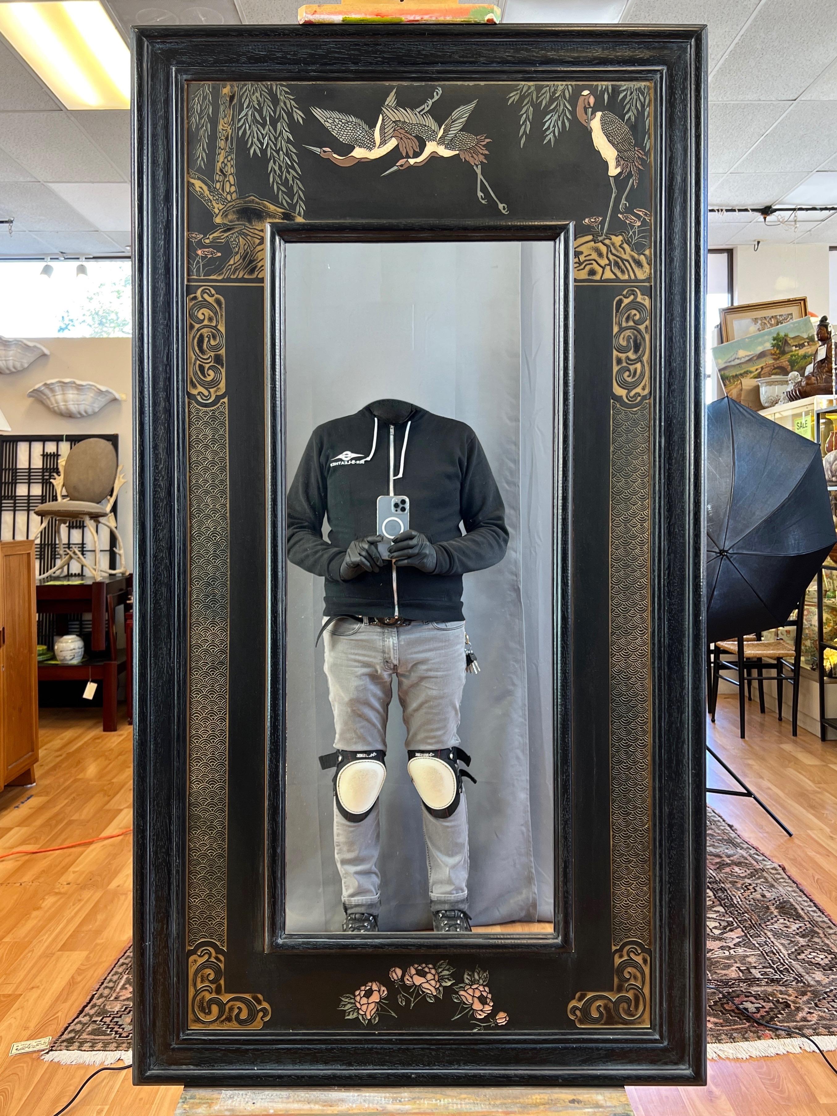 An exquisite late 1970s Asian black cerused wood wall mirror with relief carved Japanese crane and camellia flower motif.

Black lacquered cerused wood frame around a hand-carved and painted satin black panel relief featuring a variety of nearly