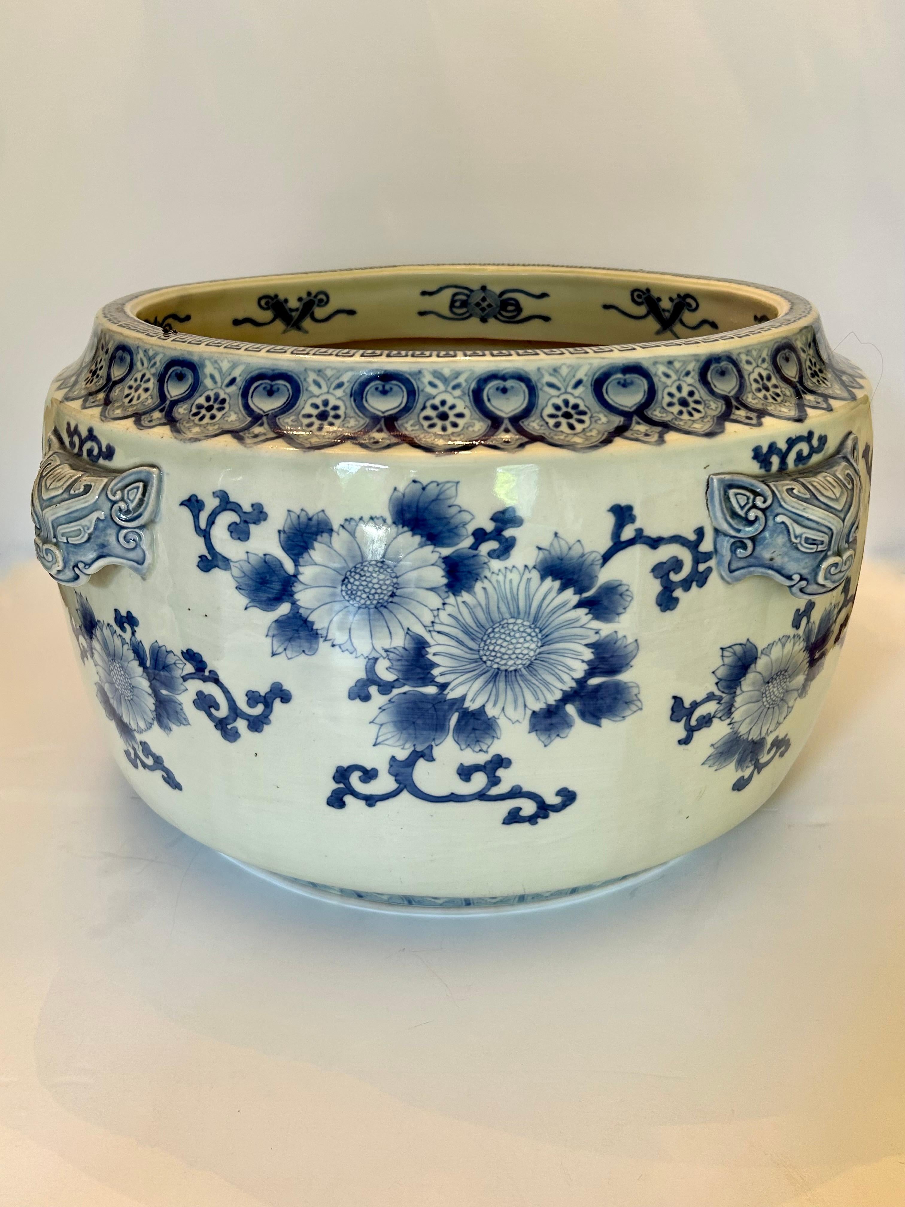 Une grande et belle jardinière japonaise Imari de la période Meiji, 19e siècle. Magnifique décor floral bleu et blanc avec quatre anses en forme de masque. Cette jardinière est dotée d'une élégante base en bois dur. 
Cette pièce est superbe avec une