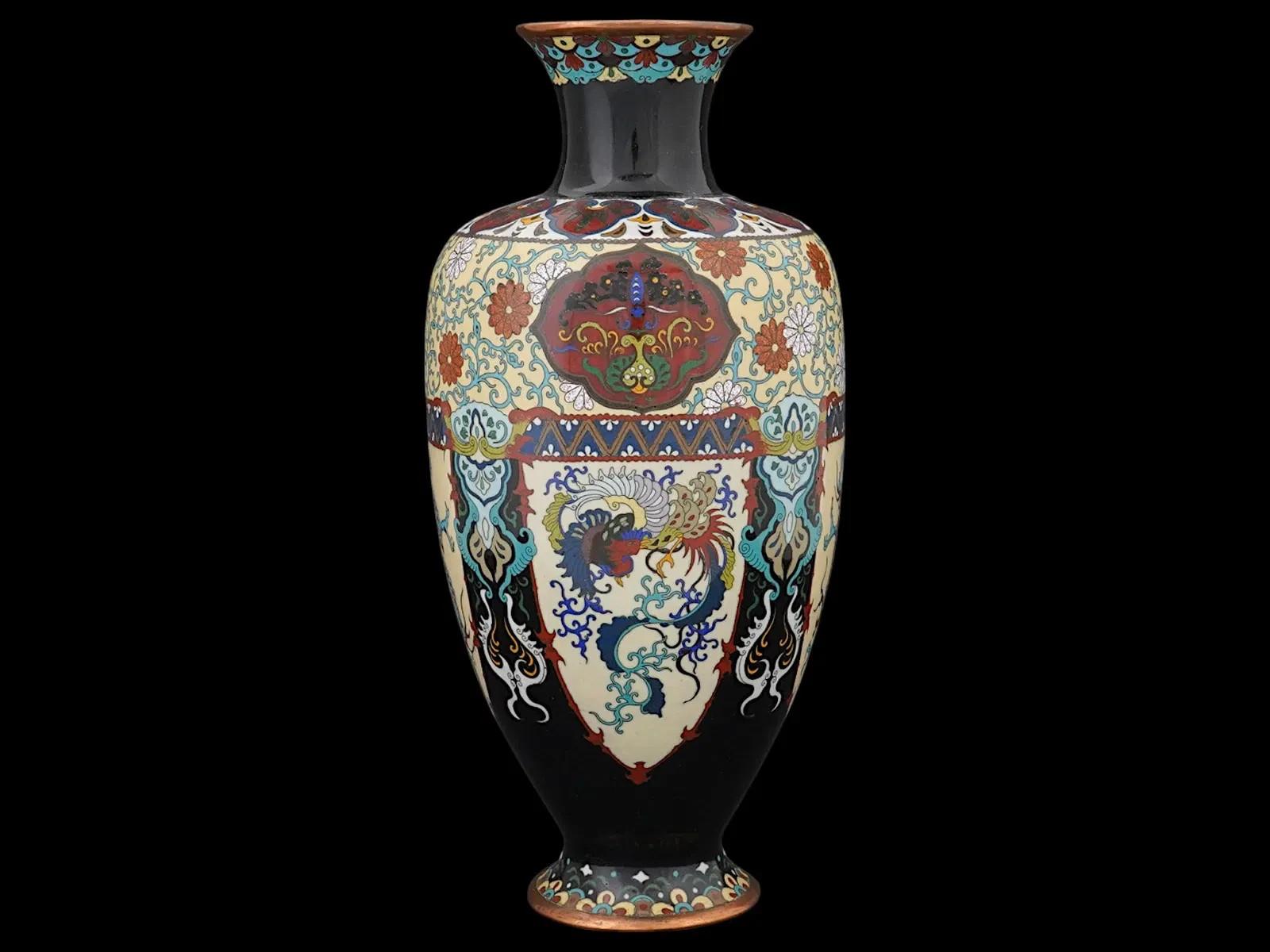 A vintage Japanese black cloisonne enamel vase. Circa mid to late 19th century. The wide vase, raised on a base, with a tapered neck that widens slightly toward the top. It is lavishly decorated with medallions, floral and foliate motifs, and images