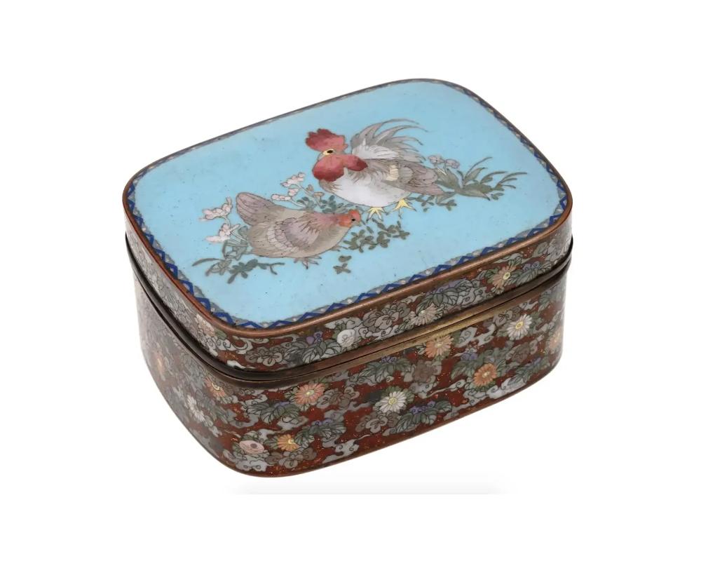 A large antique Japanese Meiji Era covered enamel over brass trinket or jewelry box. The ware is adorned with polychrome floral, and foliage patterns made in the Cloisonne technique. A lid is enameled with a polychrome image of a rooster and a hen,