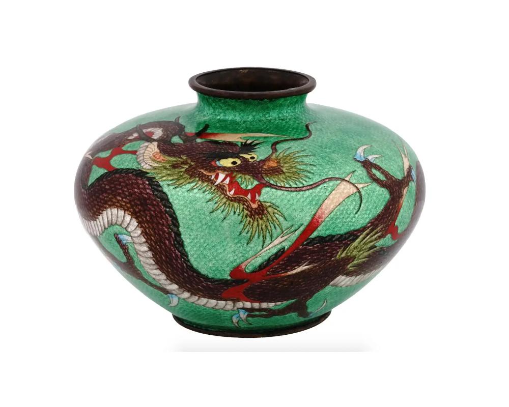 A large antique Japanese Meiji period Ginbari enamel vase. The vase has a globular shaped body and a wide neck. The ware is enameled with a polychrome image of a dragon on the green ground made in the Cloisonne technique. Ginbari is a Japanese