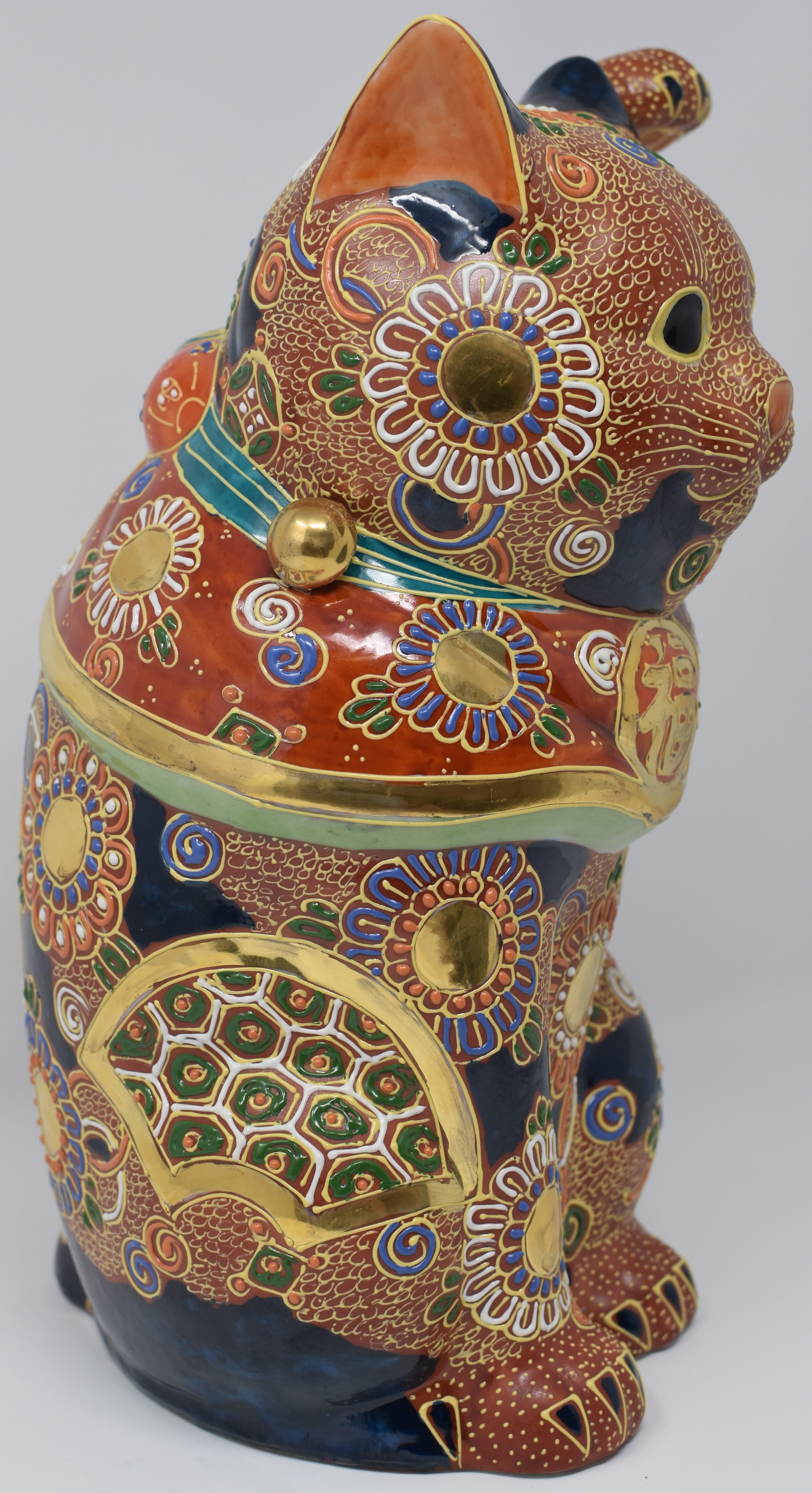 Large contemporary Japanese beckoning cat, a gilded and hand-painted porcelain piece from the Kutani region of Japan. The cat is adorned with multiple golden medallions and is covered with raised loops characteristic of the Kutani “moriage” style.