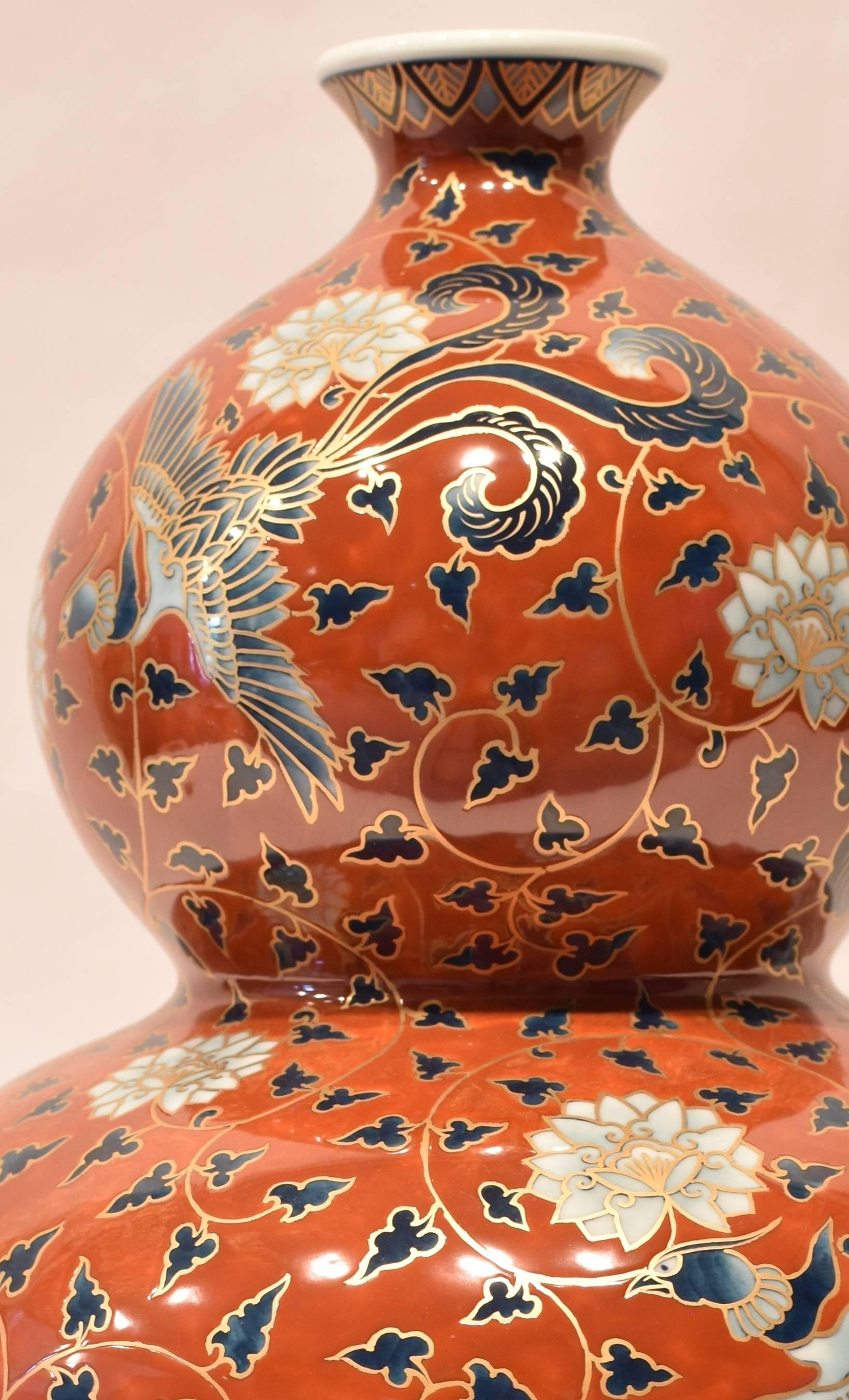 This unique striking hand-painted contemporary Japanese porcelain vase is presented in an auspicious double-gourd form in red and combines an arabesque motif with birds and flowers set against a brilliant red background. It highlights highly ornate