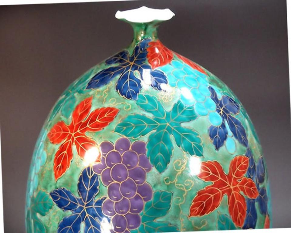 Contemporary Japanese decorative porcelain vase, hand painted on a stunningly shaped porcelain body in green with mesmerizing grape and vine motif in vibrant red, blue and green, asigned work by widely acclaimed award-winning master porcelain artist